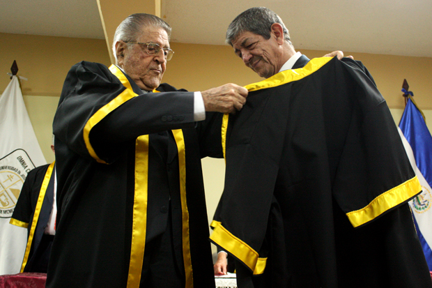 René Fortín, Vicepresidente del Consejo Directivo de la UJMD, entrega la toga a Chus Visor durante la ceremonia del Doctorado Honoris Causa