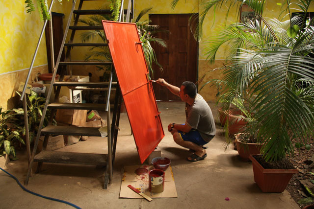 El párroco de San Luis de la Reina, Edgardo Hernández, pinta una puerta en el patio de la parroquia.