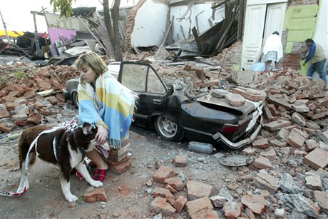 Un mujer se sienta en frente de su casa reducida a escombros en Talca, Chile. Foto AP