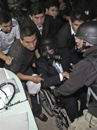 El presidente de Ecuador, Rafael Correa, sentado en una silla de ruedas y portando una máscara antigás, es rescatado de un hospital donde estaba atrapado por policías sublevados en Quito, el jueves 30 de septiembre de 2010. Foto AP