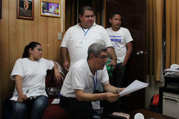 William Huezo revisa estadísticas oficiales en su cuartel general, mientras su diputado suplente, Carlos Rodas y algunos de sus ayudante sintonizan los resultados en un programa de televisión.