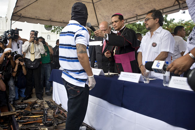 El obispo castrense Fabio Colindres ofrece el micrófono a un pandillero que declaró que la entrega de armamento es la confirmación de un proceso de pacificación de las pandillas.
