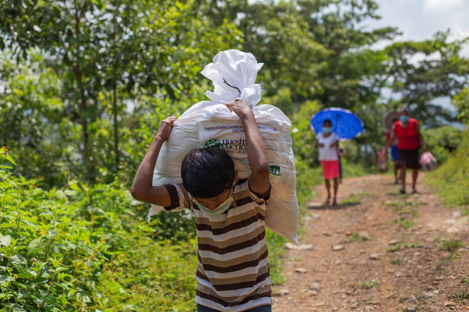 A boy carries a sack of food delivered by the Honduran Red Cross to his family. He will walk at least a half-hour to his house. Curarén, Francisco Morazán, August 27 2020. Photo: Martín Cálix