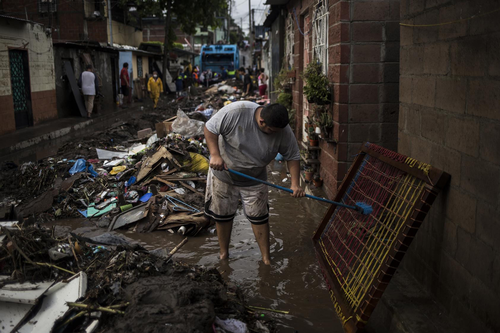 David Salguero lava lo que quedó de su cama en uno de los pasajes de El Granjero II. El río inundó todas las casas y destruyó la mayoría de pertenencias de los habitantes el domingo 31 de mayo. La comunidad no tiene acceso al agua potable desde el 28 de mayo. Un camión dañó las tuberías que abastecen esa zona y aún no han sido reparadas. foto de El Faro: Víctor Peña. 