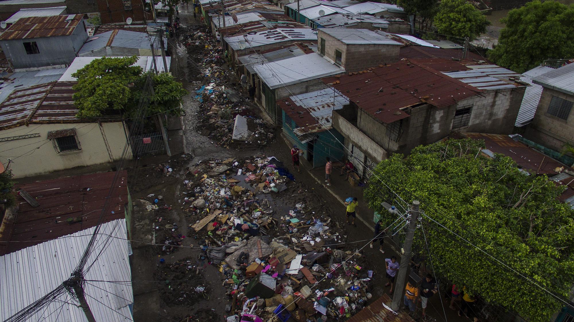 Esta no es la basura que el río arrastró. Son las pertenencias de las familias afectadas por la tormenta tropical Amanda. Las calles y pasajes de esta comunidad ahora son un cúmulo de lodo, agua y escombros que la gente ha ido rescatando de sus hogares. Foto de El Faro: Víctor Peña.