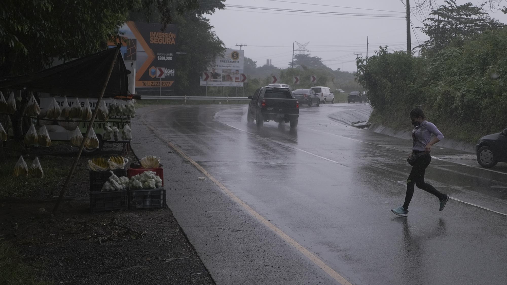 Karen Mineros corre bajo la tormenta después de vender una bolsa de guineos. Por cada dólar vendido ella gana 25 centavos. En sus mejores días, Karen vende 30 bolsas con fruta, los que le genera un poco más de siete dólares.