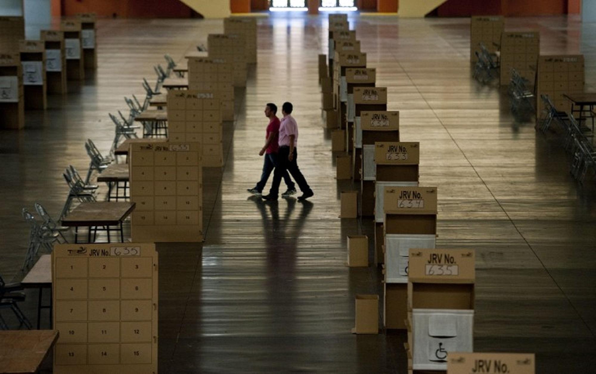 Election officers walk by polling booths at the International Fairs and Convention Center in San Salvador, El Salvador on February 1, 2014, during preparations on the eve of the presidential election. AFP PHOTO/ Jose CABEZAS
