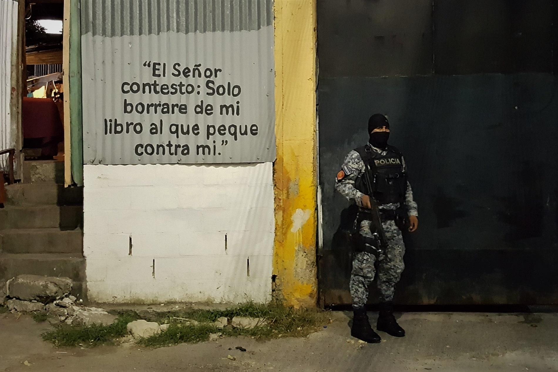 Un agente de la PNC custodia el portón de la comunidad Colfer, en el barrio San Jacinto de San Salvador. Foto Roberto Valencia.