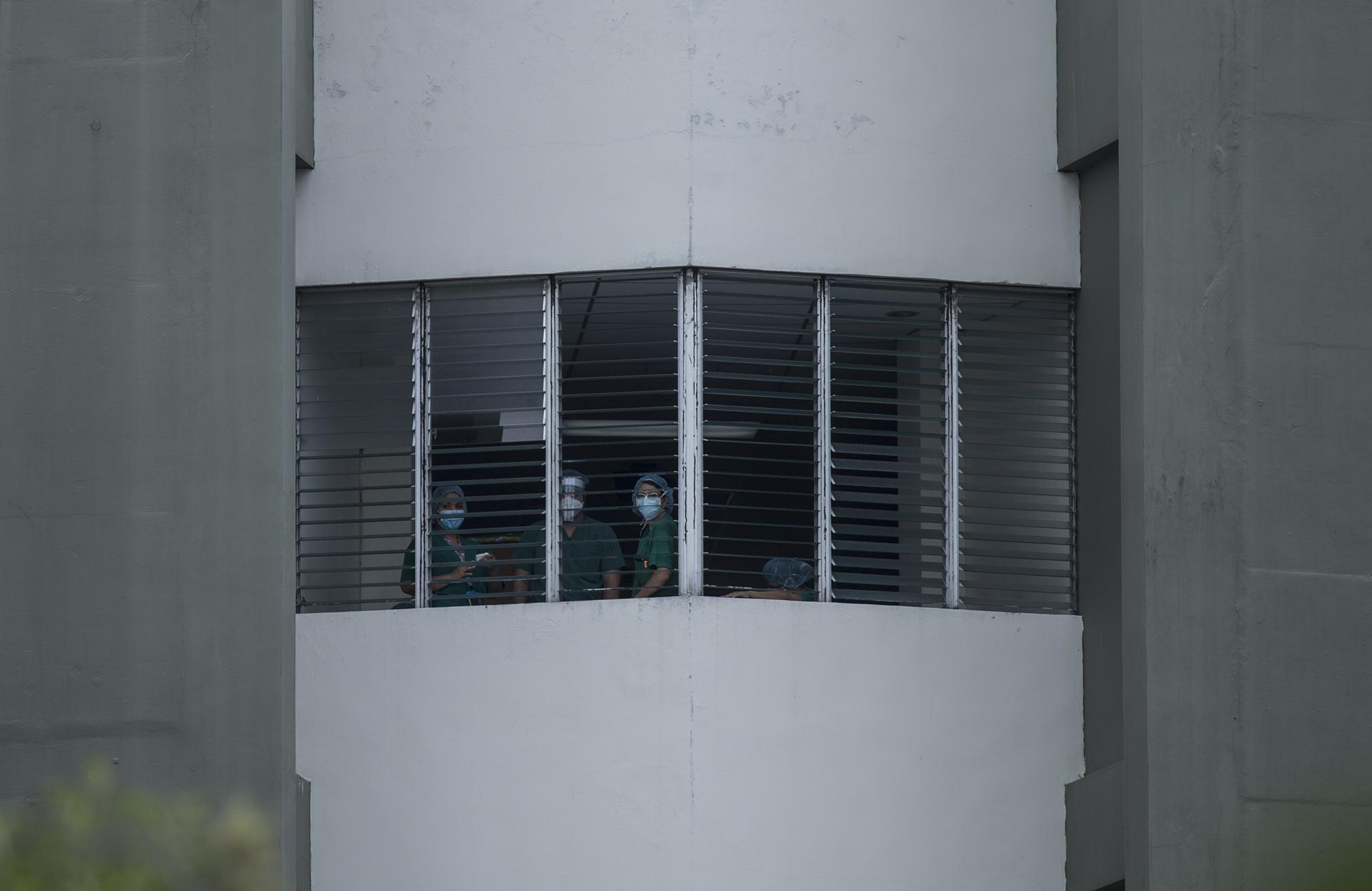 Los miembros de una iglesia evangélica realizaban una campaña de oración frente al hospital San Rafael de Santa Tecla, la mañana del domingo 17 de mayo de 2020. Personal médico se acercó a las ventanas para escuchar la oración. Foto de El Faro: Víctor Peña.