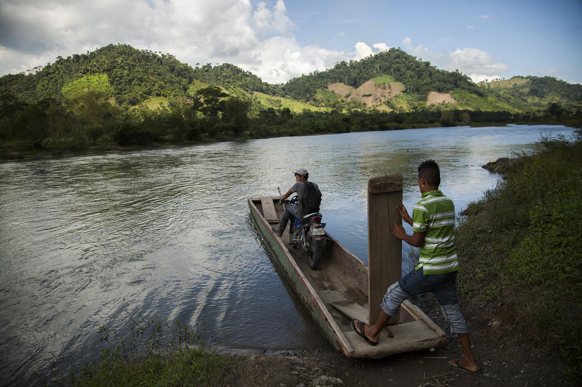 Un cayuquero traslada a un habitante por el río Leán, en Atlántida, Honduras. El joven cayuquero asegura que los habitantes han decidido no bañarse río abajo debido a la contaminación que causa una planta procesadora de Dinant, una de las principales productoras de aceite de palma. / Foto El Faro: Víctor Peña