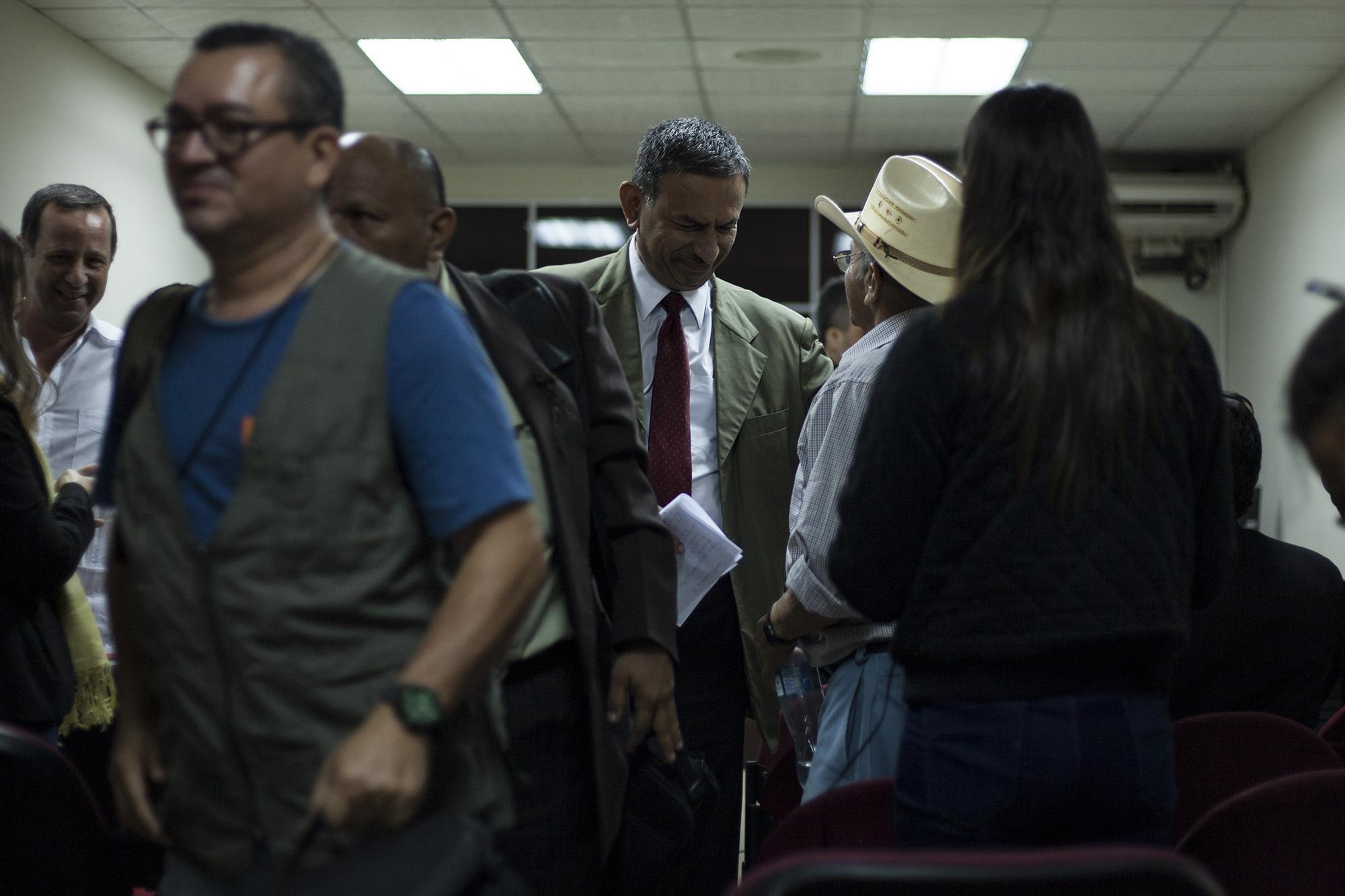 El abogado Rodolfo Garay Pineda (de chaqueta verde olivo y corbata roja), defensor de dos coroneles imputados por El Mozote, intercambia palabras con el testigo Genaro Sánchez, en un receso de la audiencia del 28 de septiembre, en el juzgado de San Francisco Gotera, en Morazán. Foto de El Faro, por Víctor Peña.