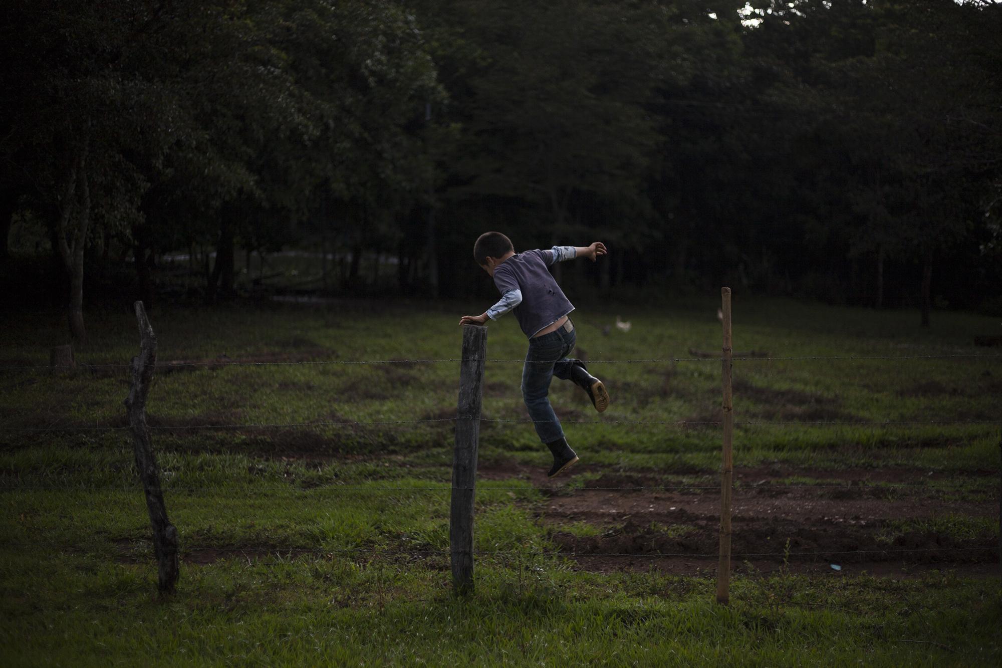 Owen Márquez juega cerca de los alambres que separan su vivienda, ubicada a unos 100 metros de la iglesia parroquila del caserío l Mozote. Owen tiene siete años, y 36 años después de la masacre, juega muy libre sobre un terreno donde fueron asesinadas casi mil personas. Foto de El Faro, por Víctor Peña.