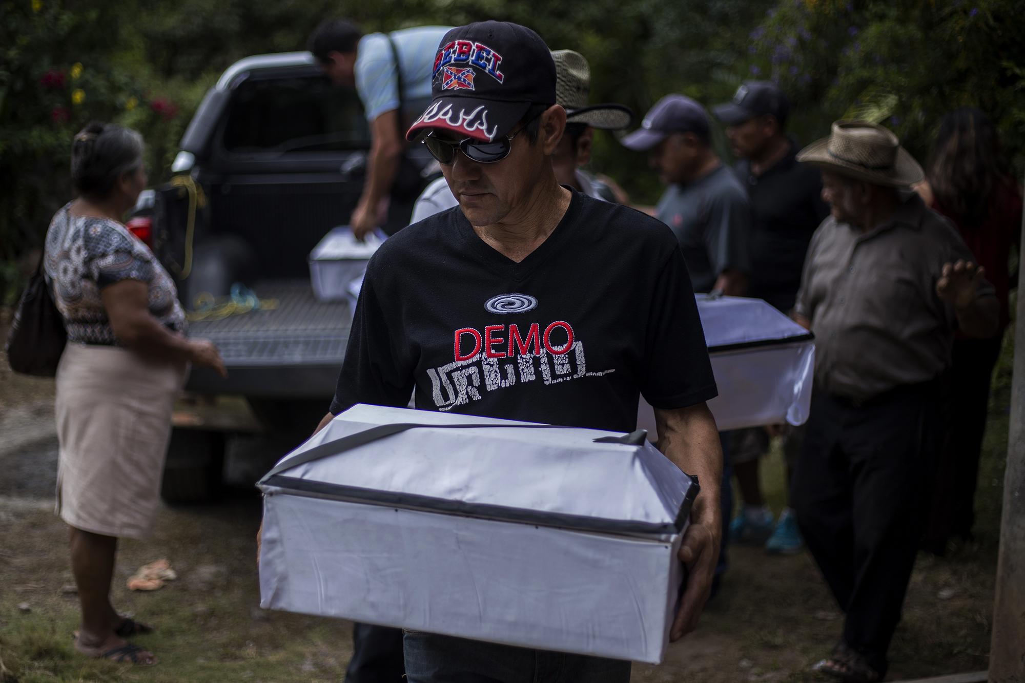 Marcial Vigil, sobreviviente de la masacre, carga a una de las seis víctimas durante el sepelio, en el cantón La Joya. Foto de El Faro, por Víctor Peña.