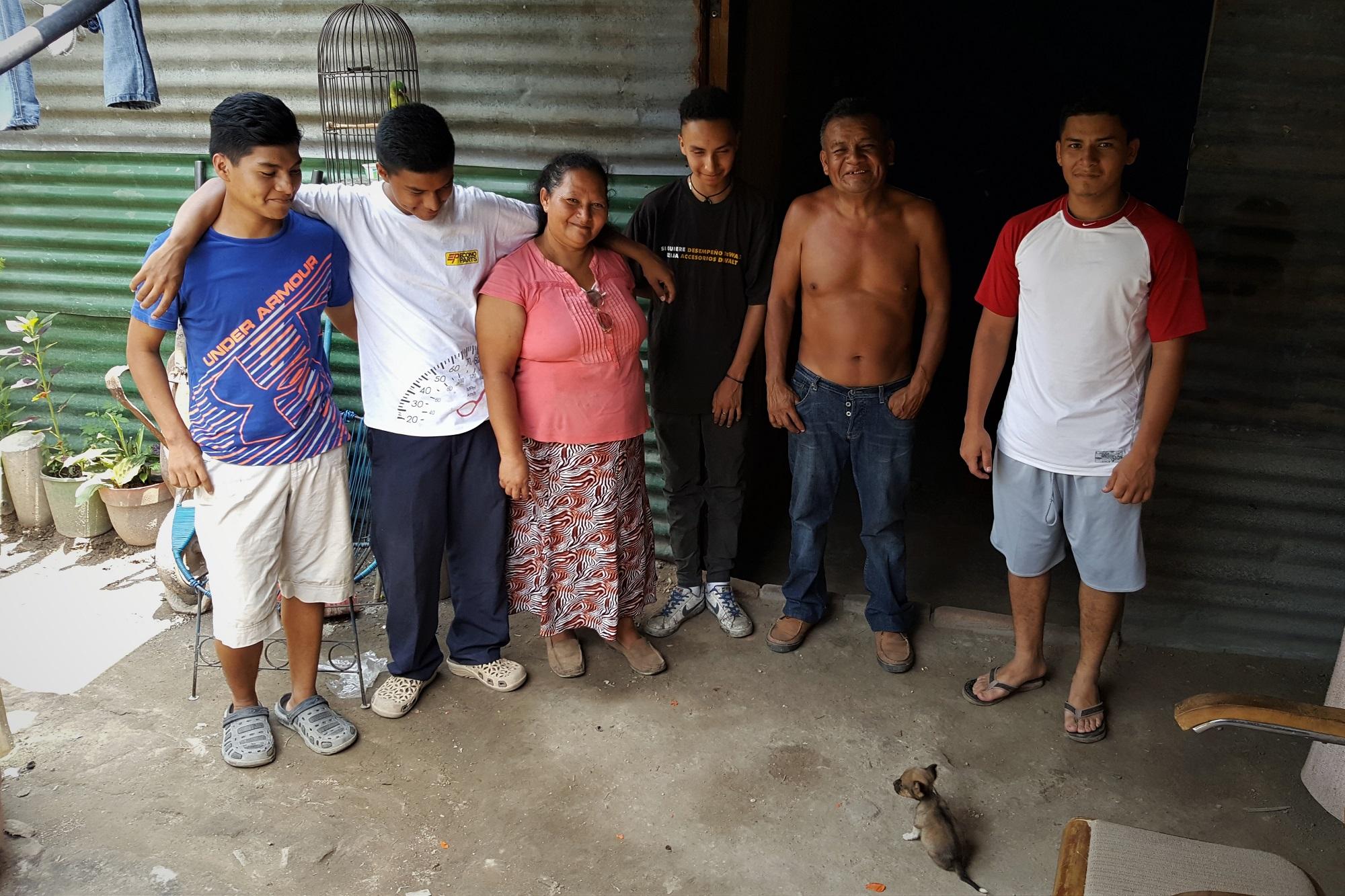 Rosalinda Singüenza, su esposo Armando De León y cuatro de los hijos posan frente a la champa que levantaron con láminas donadas para tener un lugar en el que dormir. Otras tres personas viven en ese hogar; nueve, por todo. Antes del incendio, el lugar en el que están parados era parte de la vivienda techada. Foto Roberto Valencia (El Faro).