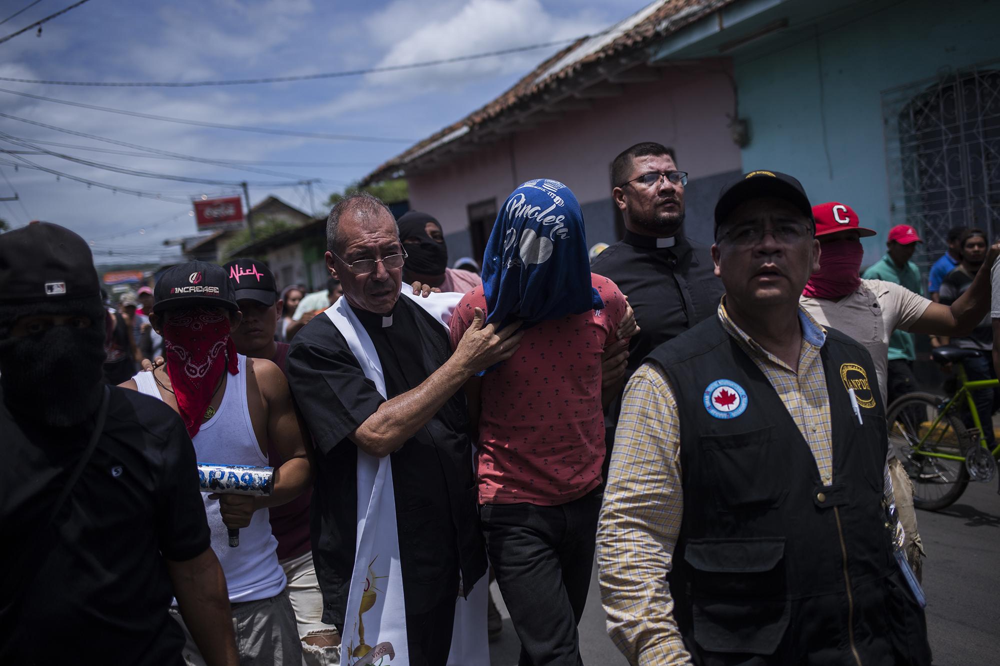 Edwin Román, sacerdote de la iglesia San Miguel, y Álvaro Leiva, de la Asociación Nicaraguense Pro Derechos Humanos, llegan a la Policía de Masaya para hacer entrega del hijo de un agente de la policía, que las turbas habían detenido y mantuvieron secuestrado. Foto de El Faro, por Víctor Peña.