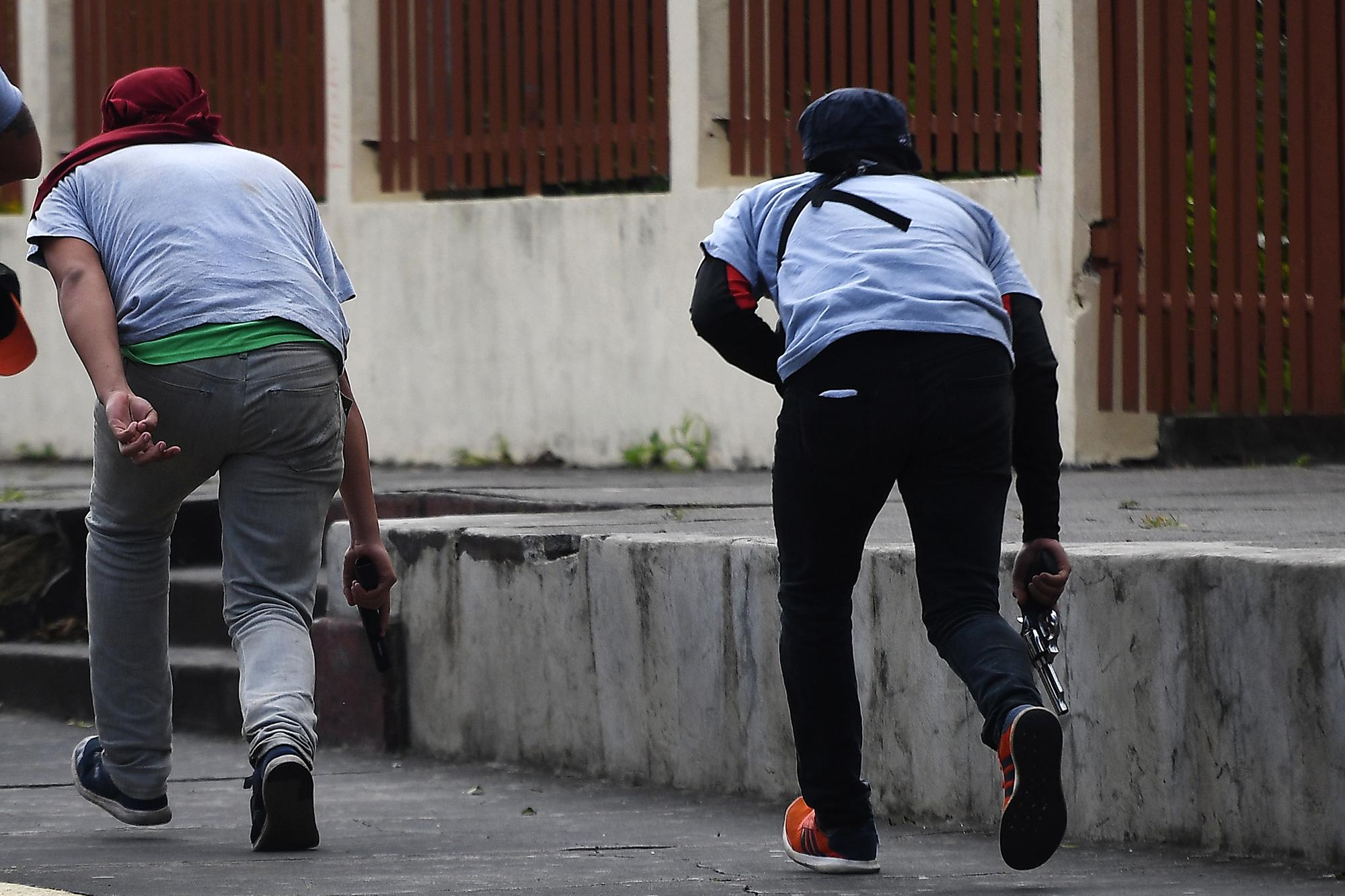 Paramilitares rodean la Basílica de San Sebastián, en Diriamba, Nicaragua, el 9 de julio de 2018. Partidarios armados del gobierno del presidente nicaragüense Daniel Ortega irrumpieron en la basílica, asediaron e insultaron a los obispos que habían llegado antes a Diriamba. / AFP PHOTO / MARVIN RECINOS