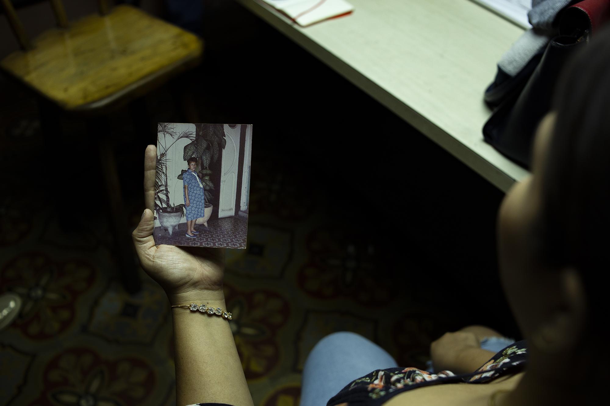 Carla Barrios muestra una fotografía de su madre mientras explica la época en la que ellos vivieron en el club. Nunca ha sentido vergüenza del lugar de trabajo de su papá, pero prefiere no dar la cara por motivos de seguridad.