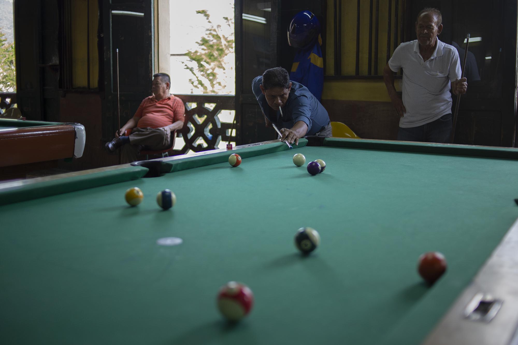 Un grupo de hombres juega una partida de billar en la Dalia. Desde que la nueva ola de visitantes llegan al local, es usual que se quejen por no tener suficiente espacio para manipular el taco.