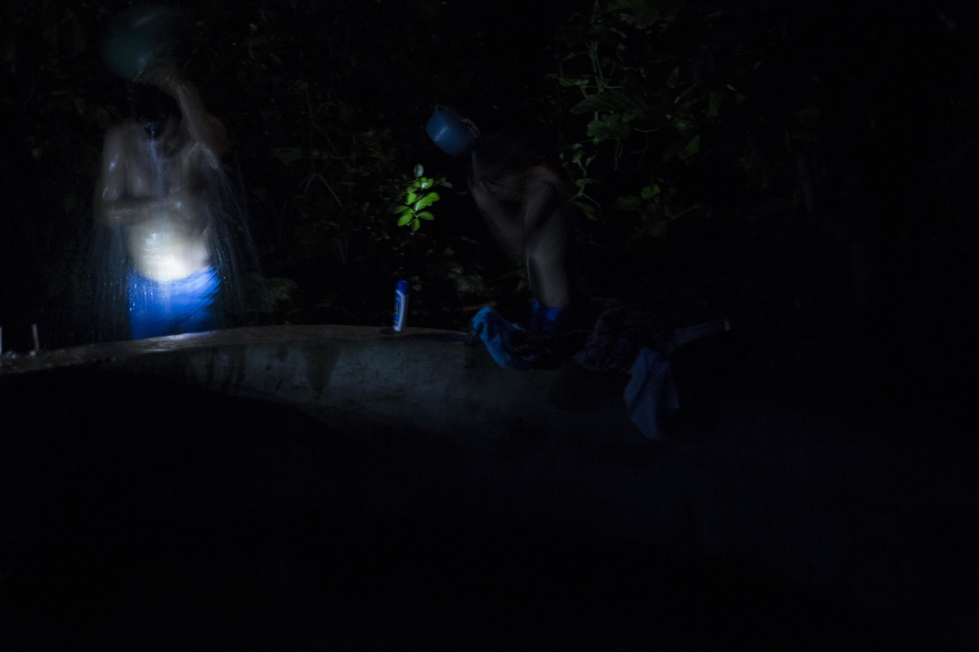 A las 5 de la mañana, Tránsito Rivas (izquierda), de 45 años, se baña junto a su hijo Óscar, de diez años, para comenzar la jornada del día. Esta familia almacena agua lluvia que se mezcla con tierra y hojas secas, en un estanque de cemento de dos metros de profundidad y cuatro de diámetro, ubicado a unos diez metros de la vivienda. En el cantón La Uvilla, del municipio de Ciudad Victoria, en el departamento de Cabañas, sus habitantes nunca han disfrutado el agua potable.