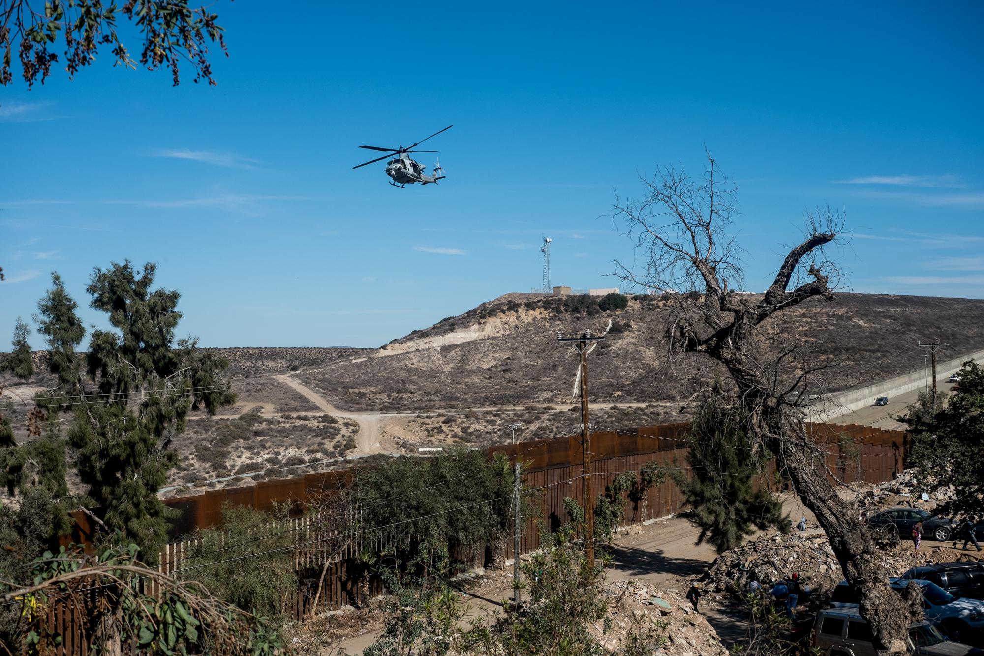 Un helicóptero estadounidense vuela sobre la frontera entre Tijuana y San Diego el domingo 25 de noviembre, mientras cientos de migrantes rondaban el muro. algunas latas de gas lacrimógeno fueron lanzadas desde los helicópteros hacia territorio mexicano.  Foto: Fred Ramos