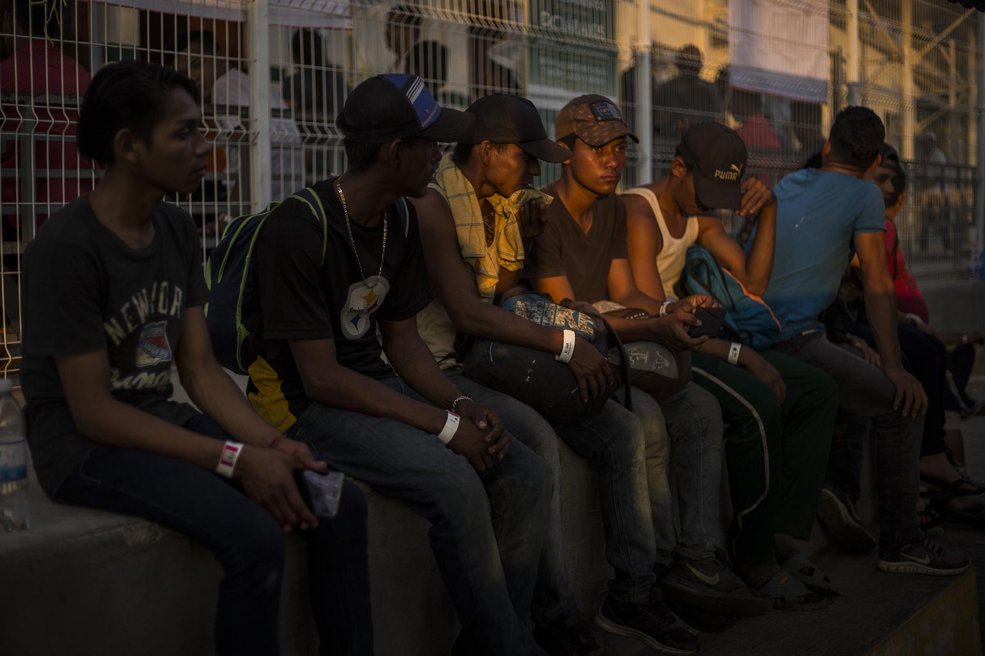 Cinco hondureños esperan turno para llenar su solicitud para una visa humanitaria, que les permitirá transitar y trabajar libremente por México durante un año. La caravana de migrantes se ha dividido en la frontera Tecún Umán entre quienes confiaron en las promesas del gobierno mexicano y quienes decidieron no hacerlo, entrar de forma indocumentada y seguir su camino hacia el Norte. Foto: Víctor Peña.