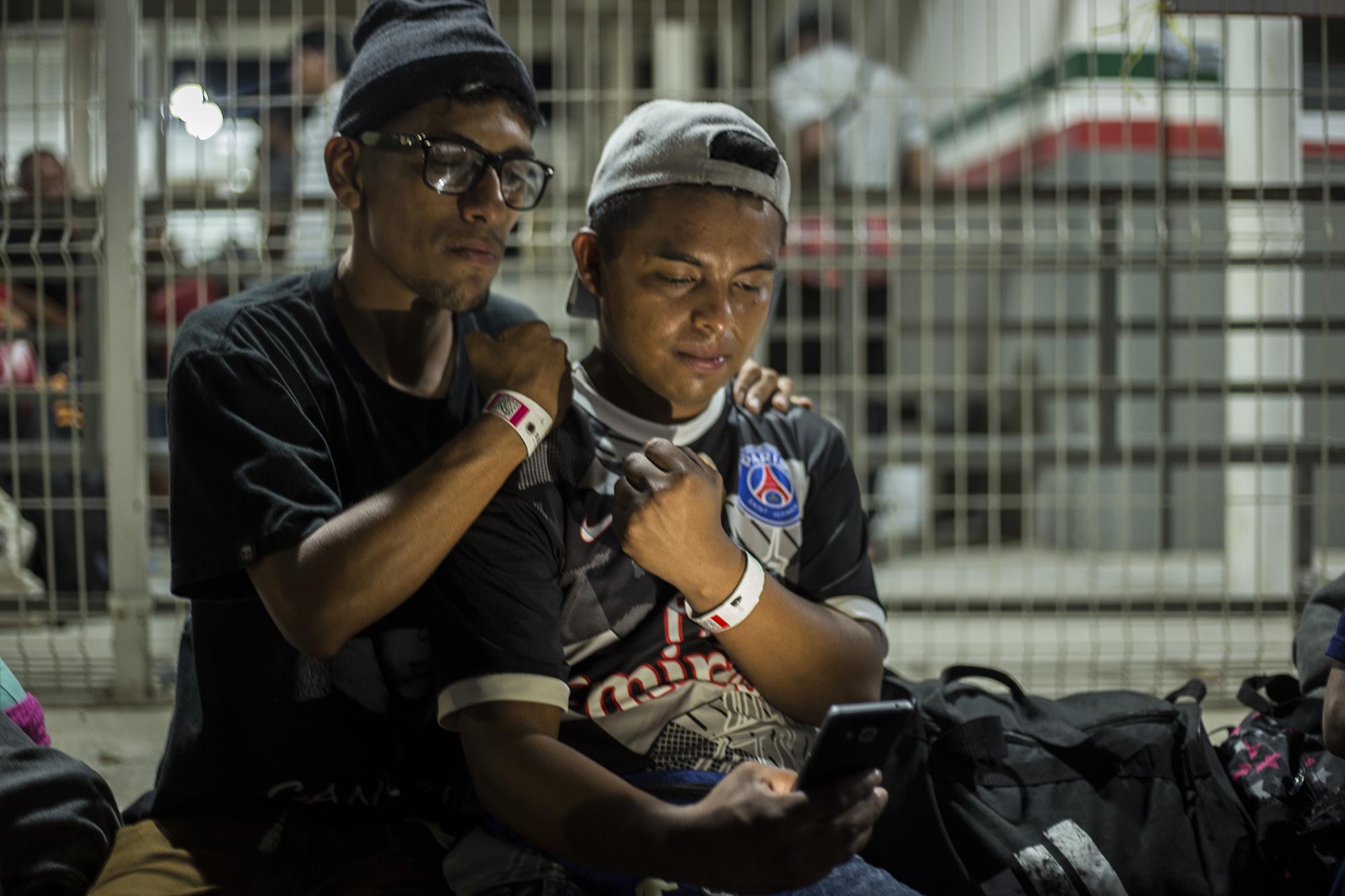 Isaac Ascencio, de 28 años (izquierda), y Vladimir Crespín, de 25, se autoretratan en la aduana Ciudad Hidalgo, tras recibir sus pulseras. Con esa pulsera es posible pasar a Ciudad Hidalgo. Los datos del migrante quedan registrados en el código que va en la pulsera y, tras un máximo de cinco días de espera, quienes la conservan reciben un documento para poder transitar por México. Ambos migrantes en la foto son salvadoreños. Isaac era vendedor de dulces en el municipio de Quezaltepeque, La Libertad. Ganaba $6 al día, después de pagar dos dólares diarios al Barrio 18, pagar sus pasajes, su comida y los dulces. Decidió caminar con su amigo, y ahora han decidido quedarse en México.
