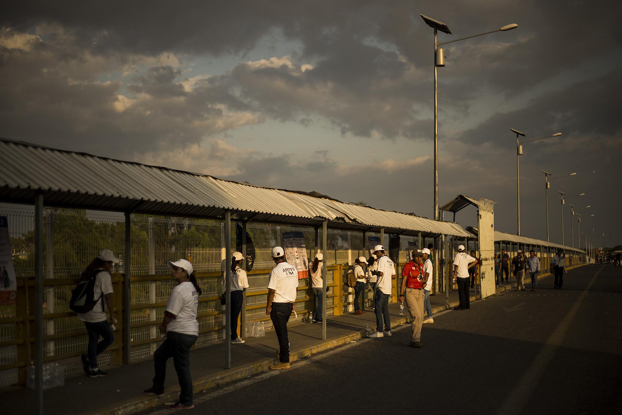 Un equipo de colaboradores del Instituto Nacional de Migración de México, permanece en la zona peatonal del puente Rodolfo Robles, sobre el río Suchiate, que divide Guatemala y México. Desde el 17 de enero de 2019, México abrió las puertes a los migrantes centroamericanos que huyen de sus países, y les ofreció un permiso que permite transitar y trabajar libremente por el territorio mexicano por un año. Foto: Víctor Peña.