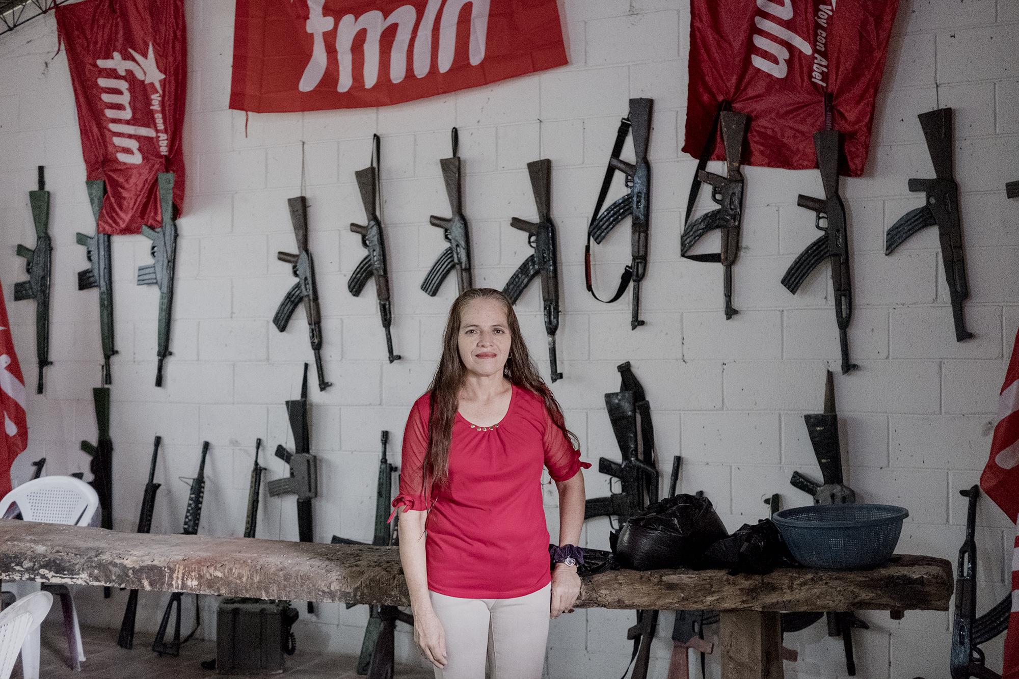 Celina Ortega Alemán, secretaria municipal del FMLN en San Antonio Los Ranchos. Ortega es de las votantes fieles a su partido. Cree que votar por otra bandera es traicionar a la sangre derramada en la guerra civil. Las armas de la foto son hechas de madera y pertrechos reales de armas de guerra. Las armas las ocupan para hacer una reconstrucción de la repoblación de Los Ranchos en 1988. Decenas de familias habían huido por el acoso militar. Poco a poco, mientras esa área se consolidaba bajo férreo control de la guerrilla, regresaron a su pueblo. Foto: Fred Ramos