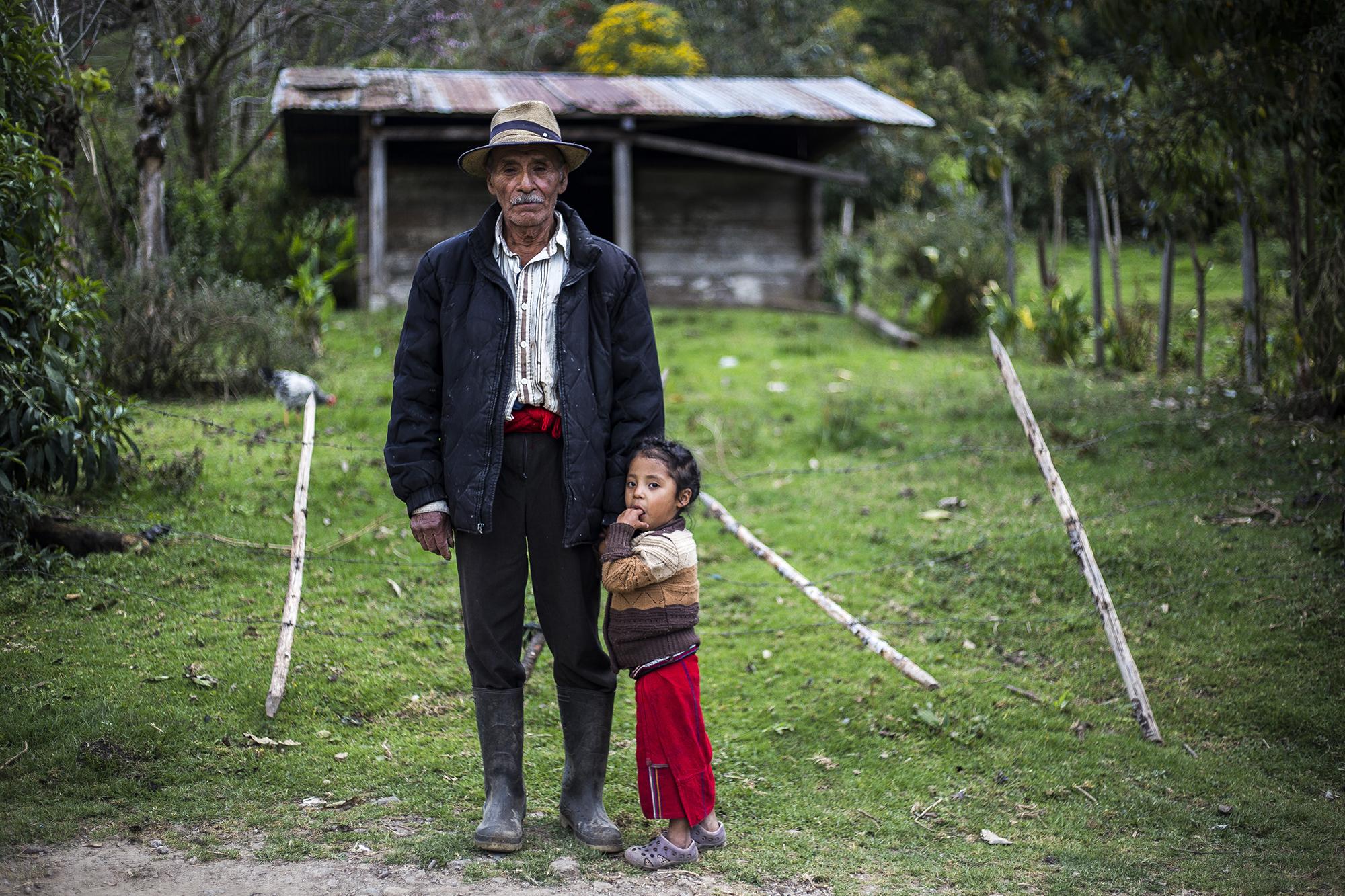 Jacinto Santiago, de 74 años, posa con su nieta, Petrona Santiago, de 3 años. Recuerda que el 17 de abril de 1981, en la aldea Cocop, juntaron los cuerpos de las víctimas y los enterraron en una fosa común. Entre ellos estaban su esposa, Juan Rivera, y sus hijos, José Santiago y Gaspar Santiago.