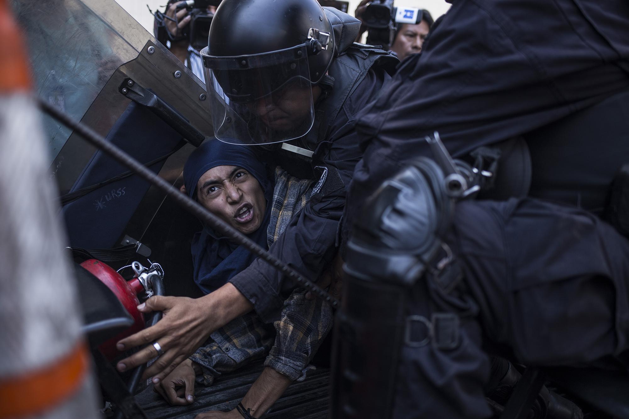 José Luis Bernal fue capturado al final de la protesta, acusado de desórdenes públicos y daño a la propiedad privada. “Me capturan por defender el derecho al agua”, sentenciaba, mientras unos cinco agentes intentaban subirlo a una patrulla. Foto: Víctor Peña.