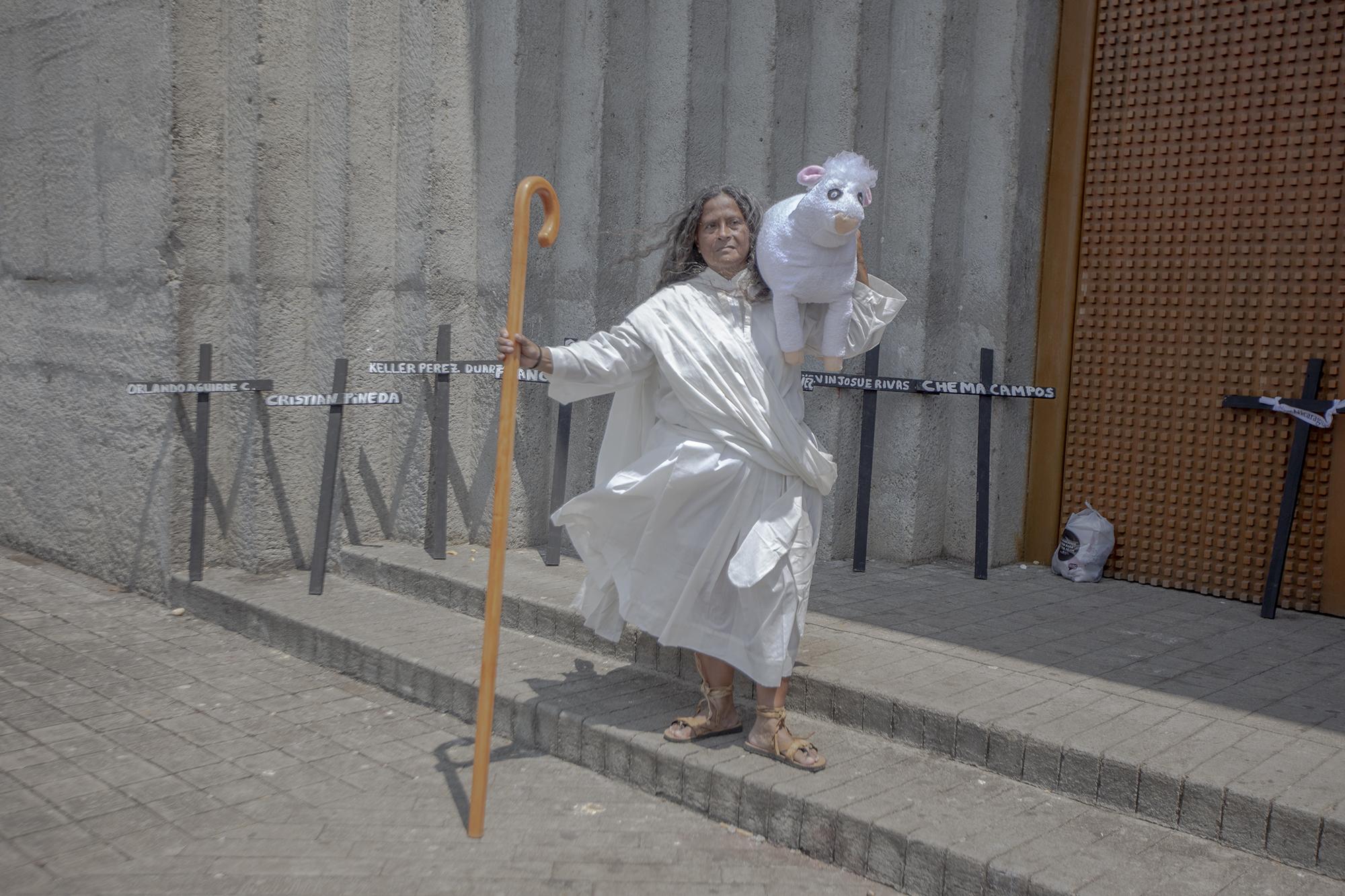 Cruces negras con los nombres de algunas de las víctimas fueron utilizadas como forma de protesta durante el viacrucis afuera de la catedral de Managua el viernes santo. Rosa María, que viste del pastor de la abundancia, posa frente a las cruces. 