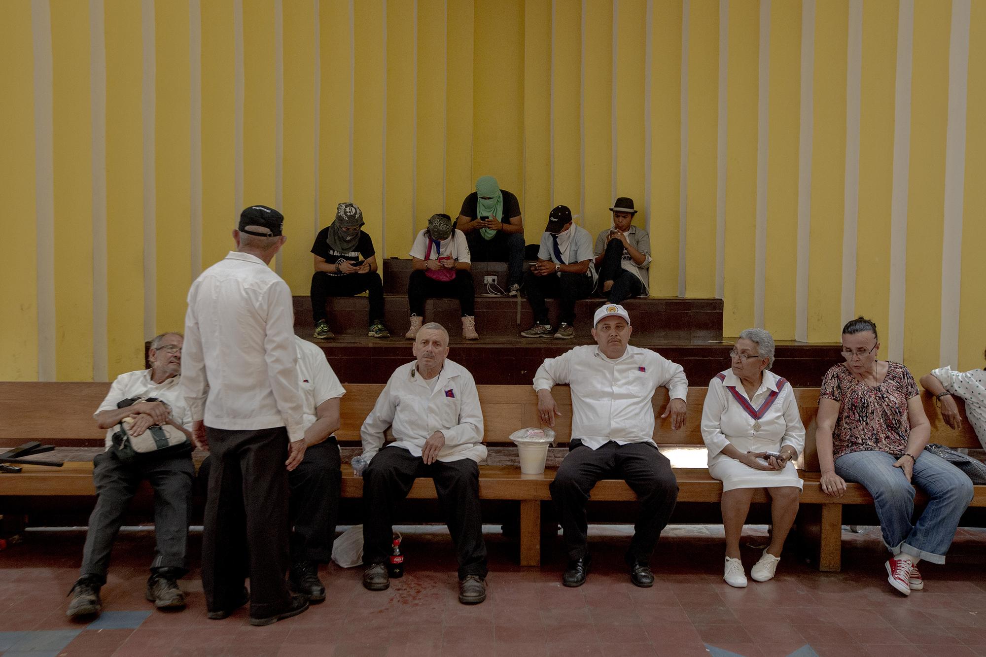 Jóvenes manifestantes (al fondo) y feligreses se resguardan de los ataques de la policía en el interior de la catedral de Managua. Al finalizar el viacrucis del viernes santo algunos de los manifestantes lanzaron piedras a miembros de la policía y estos respondieron con disparos y bombas aturdidoras. La escaramuza, esta vez, no pasó a más. 