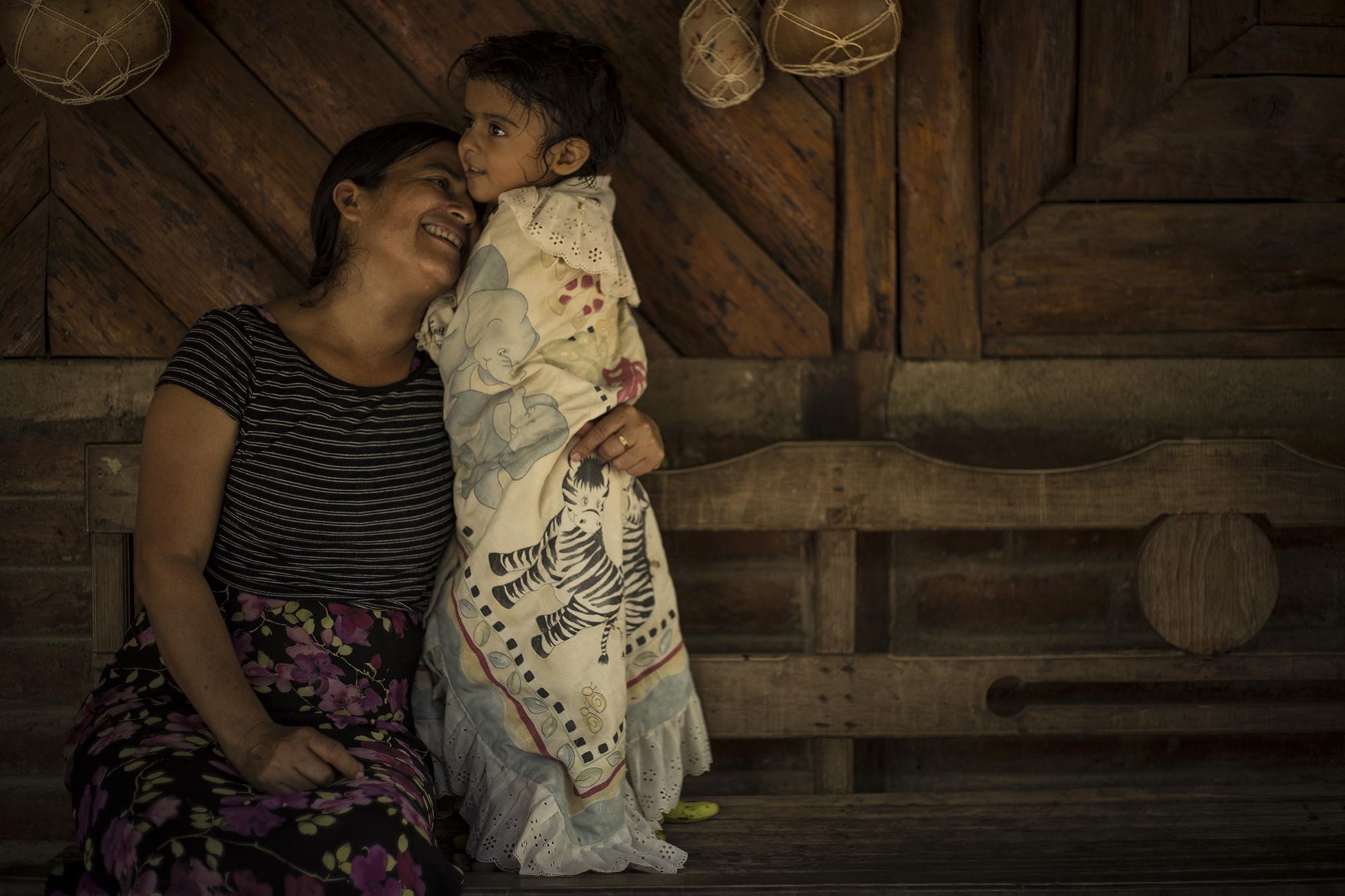 Sonia Tobar, de 47 años, junto a su hija Odalys, de tres años. Sonia fue desplazada del caserío Jocote Amarillo cuando tenía 9 años. Huyó hacia el departamento de La Libertad. Su vivienda fue destrozada durante la masacre de El Mozote y lugares aledaños. Foto: Víctor Peña.