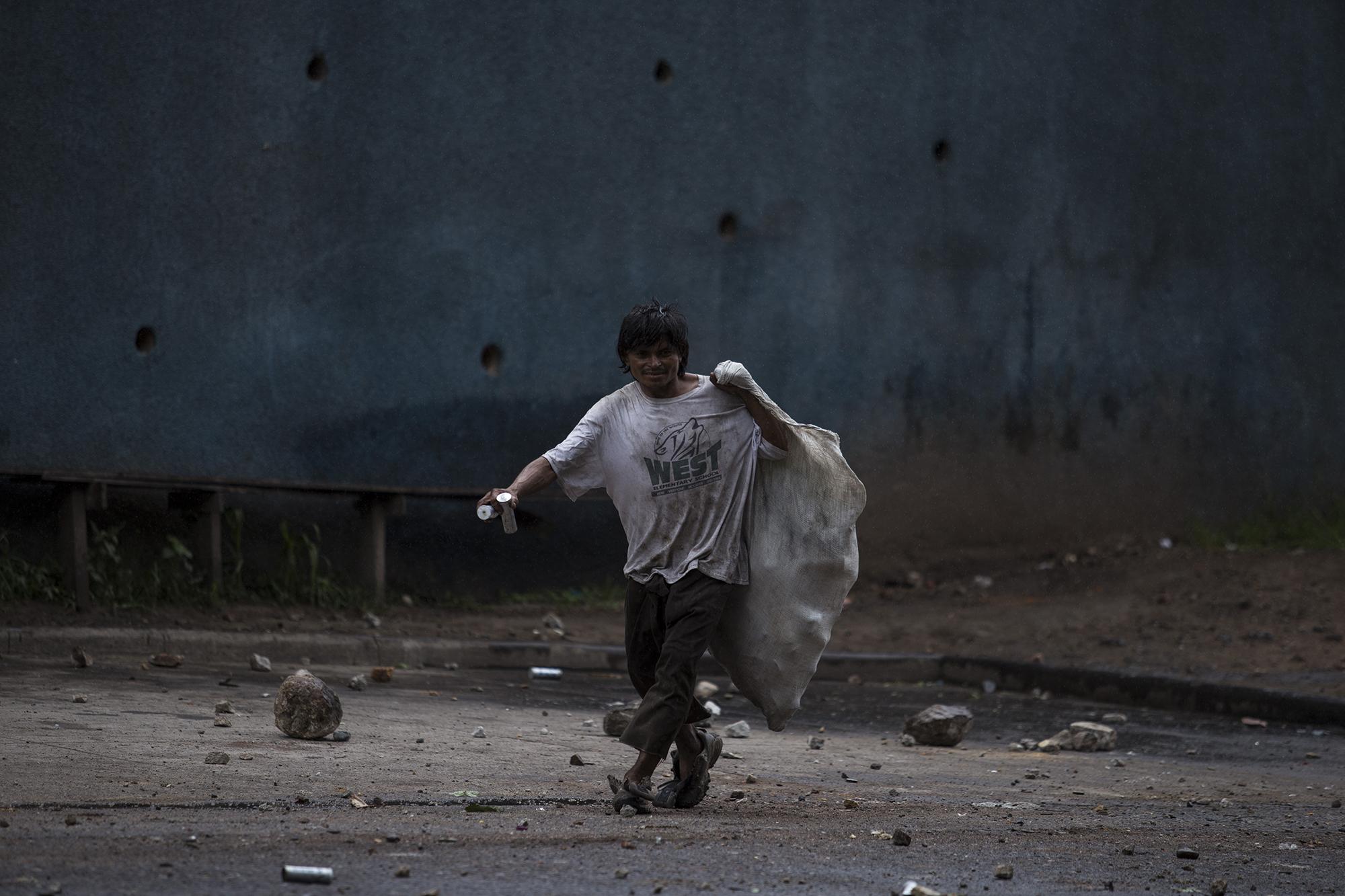 Ismael, de 32 años, se pasea después de la protesta para recoger los cartuchos de las bombas lacrimógenas. Las recicladoras de aluminio le pagan entre 3.50 y 4 lempiras por cada cartucho. Foto: Víctor Peña.