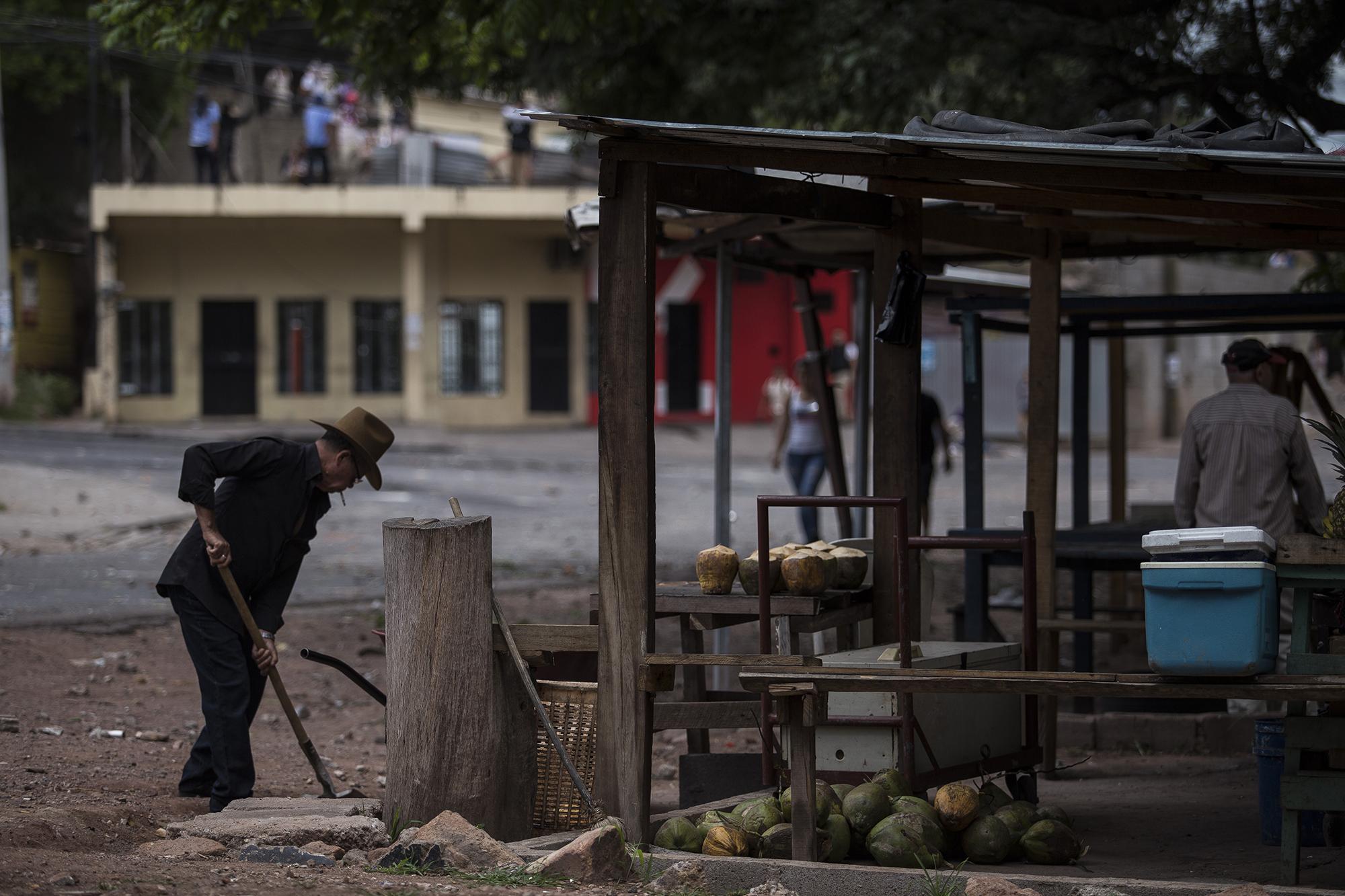 José Isabel Navarro, de 75 años, limpia su negocio de frutas. A Isabel no le preocupan los disturbios. Sigue con su negocio en medio de los enfrentamientos de estudiantes y policías, en las calles de la Kennedy. Foto: Víctor Peña.