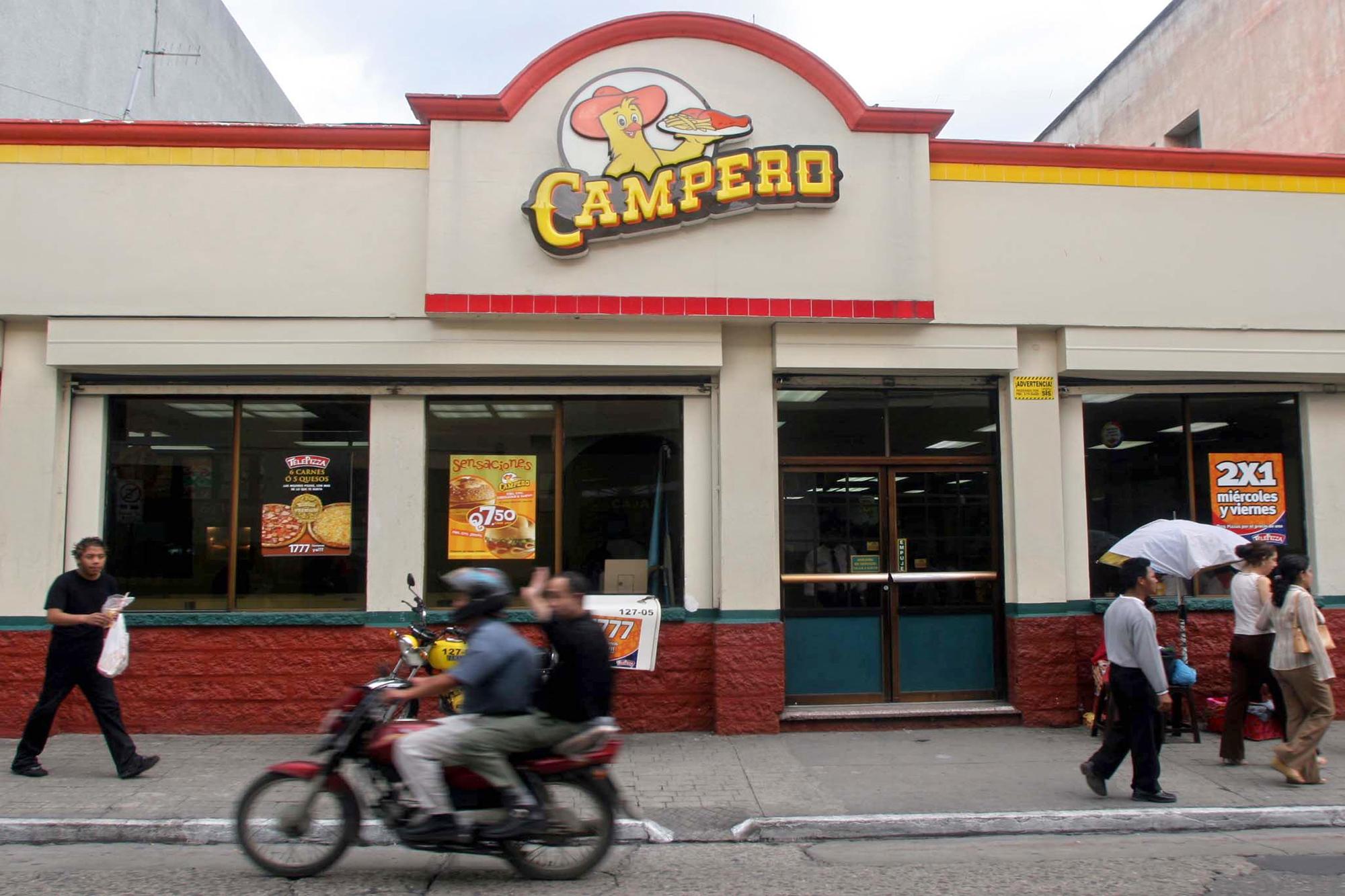 Gente circula frente a un local de la cadena de comida rapida Pollo Campero de Guatemala, en ciudad de Guatemala, el 31 de mayo de 2005. Esta es una de las más conocidas marcas de la familia Gutiérrez. Foto de AFP: Orlando Sierra.