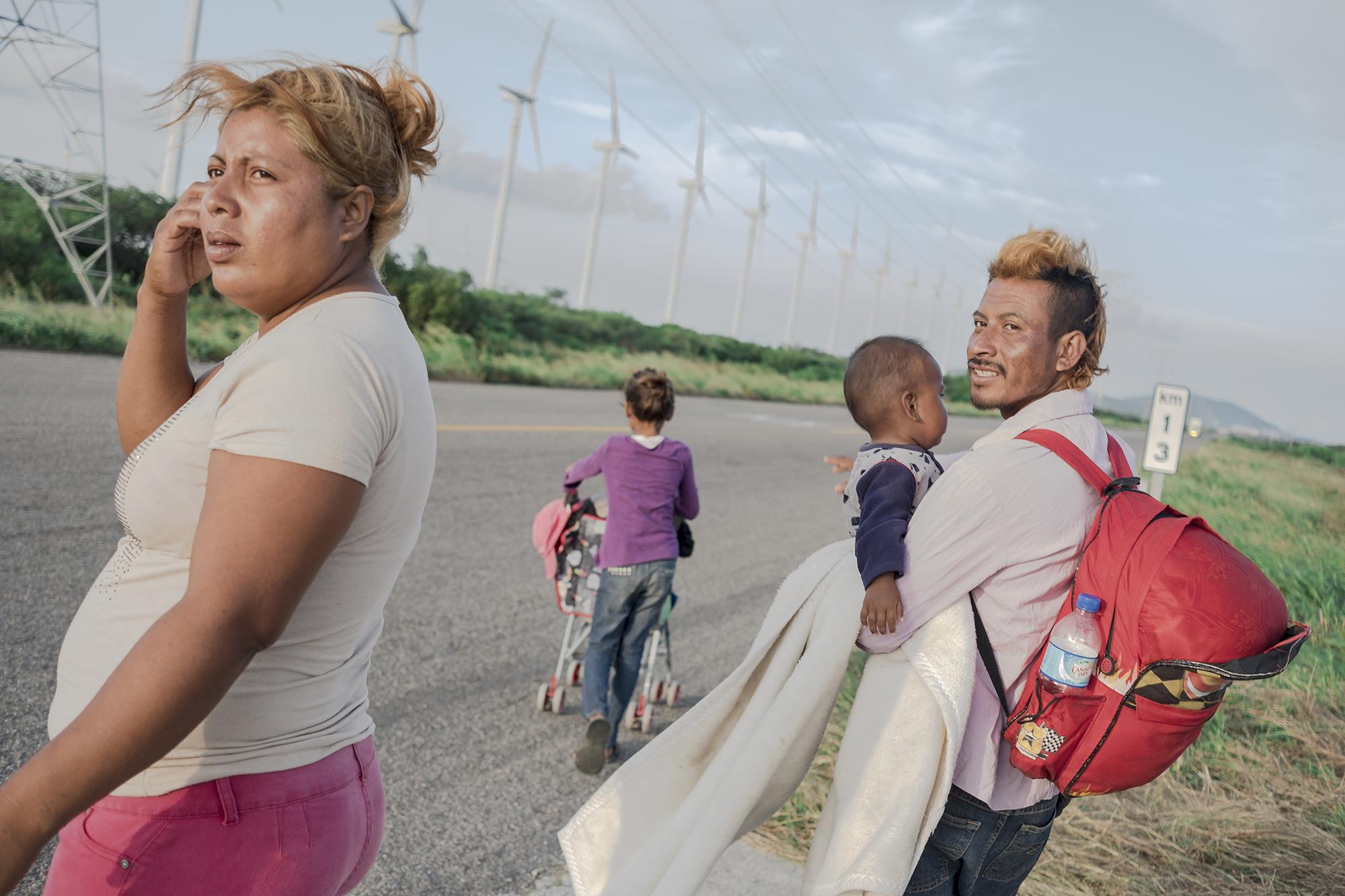 En octubre de 2018, de Honduras, El Salvador y Guatemala brotó un éxodo. Diluidas en un océano de hombres, cientos de mujeres hondureñas y salvadoreñas de todas las edades fueron parte de aquel fenómeno humano al que en la región llamó “las caravanas” y que desnudó el desgobierno de los países del norte de Centroamérica. Una avalancha de migrantes se lanzó a las carreteras y puso cuerpo al goteo migratorio que desde hace décadas transita de forma clandestina hacia Estados Unidos y que, en su paso por México, sufre asaltos, violaciones, torturas, secuestros, trata y asesinato. Ana Rafael tiene 33 años y es salvadoreña. Su marido, Luis Martínez, tiene 30. Su hijo Fernando, dos; Gabriela, la mayor, once. En la imagen, pedían aventón en la carretera México 190 para llegar a Juchitán de Zaragoza, en el estado de Oaxaca. Eran parte de la tercera caravana de personas a las que su país se les se les hizo ahogo, expulsadas por la violencia, la falta de empleo, la corrupción, las pandillas y el crimen organizado. Tras cruzar ya dos fronteras, esperaban quien los llevara en carro unos kilómetros más allá, en busca de la tercera y definitiva. En El Salvador vivían de lo que ganaba Luis como vendedor ambulante, pero Ana cuenta que en dos ocasiones los pandilleros le quitaron la mercadería y por eso decidieron migrar. Como miles de salvadoreños viajaron a Guatemala para unirse a otro grupo que había salido de Honduras el 12 de octubre y que copaba por esos días las portadas de todos los periódicos. Foto: Fred Ramos.