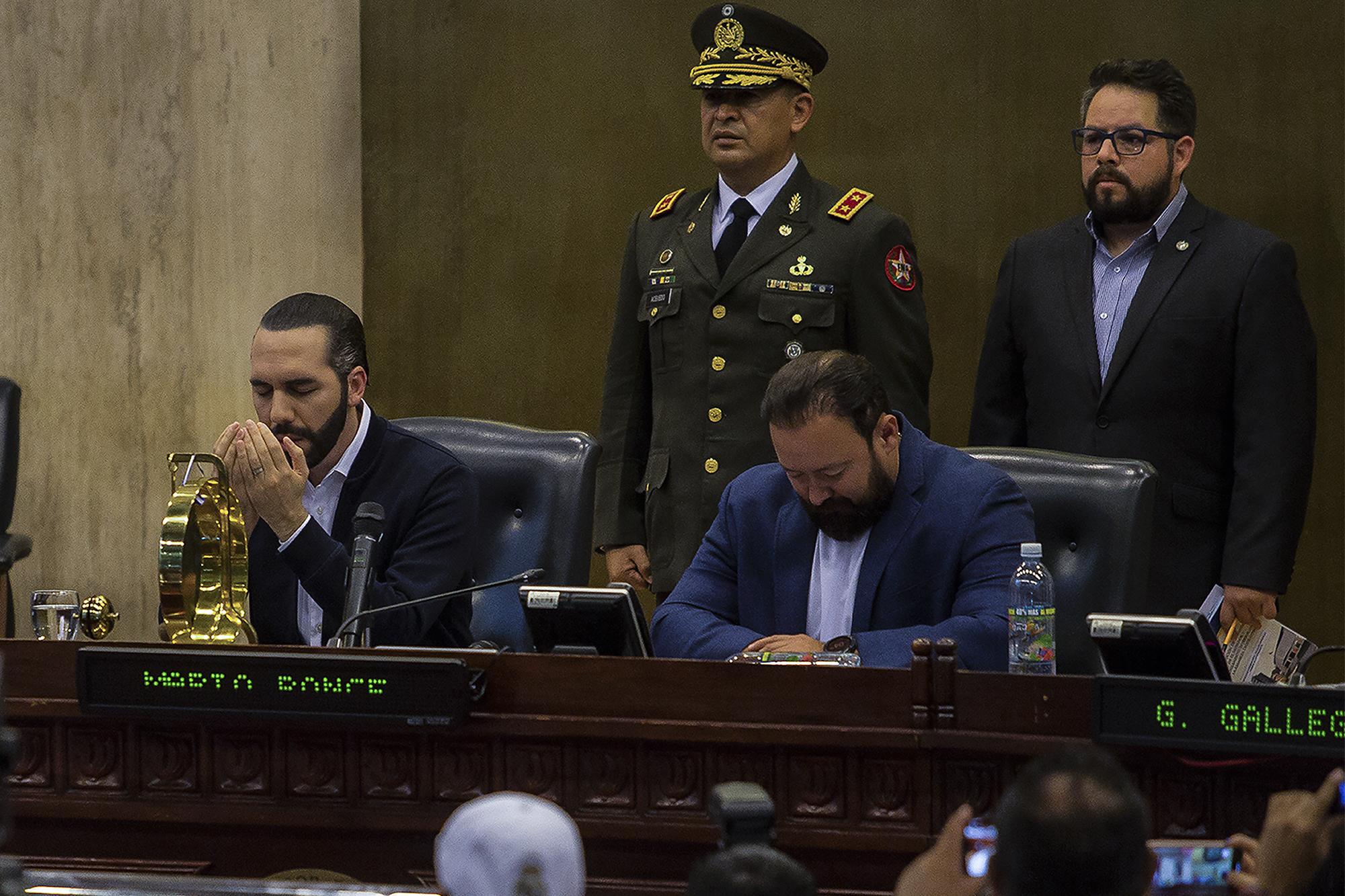 Después de amenazar a los diputados ausentes, en un Salón Azul tomado por soldados y policías, Bukele hizo una oración junto al diputado Guillermo Gallegos, de Gana. Luego, el presidente se retiró para dirigirse de nuevo a la multitud y decir que había hablado con Dios, quien le pidió paciencia. Foto de El Faro: Víctor Peña