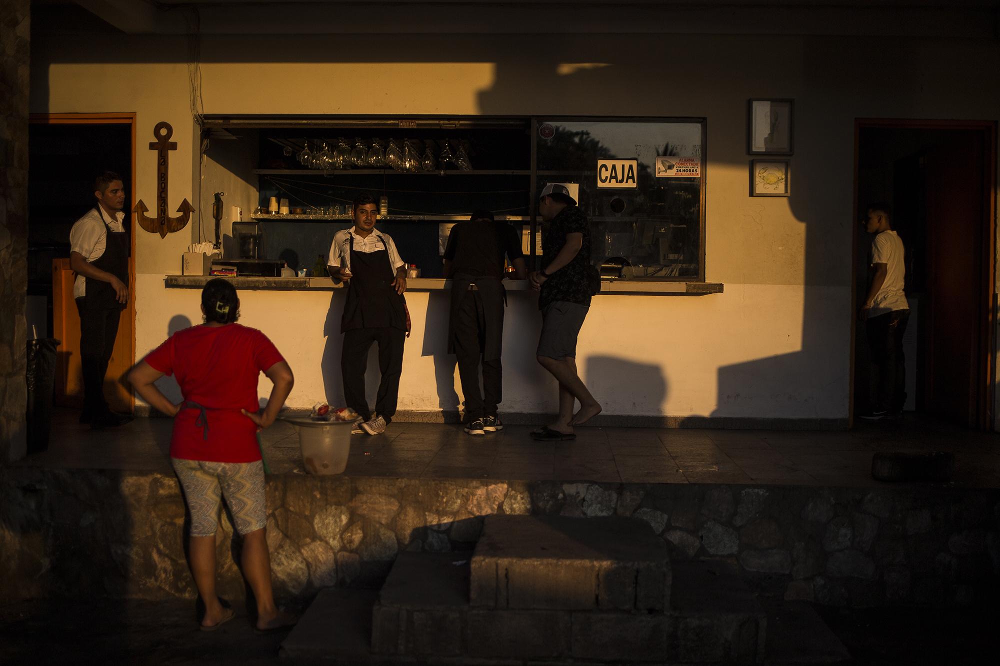 En algunas playas de La Libertad hubo actividad. Sin embargo, muchos restaurantes sufrieron la ausencia de clientes este domingo. En la carretera no existió el congestionamiento de vehículos que se extiende usualmente por diez kilómetros. En la imagen, colaboradores de un restaurante conversan al final de la tarde. Ese restaurante a la orilla del mar estaba vacío en una hora y un día que puede considerarse de alta afluencia. 