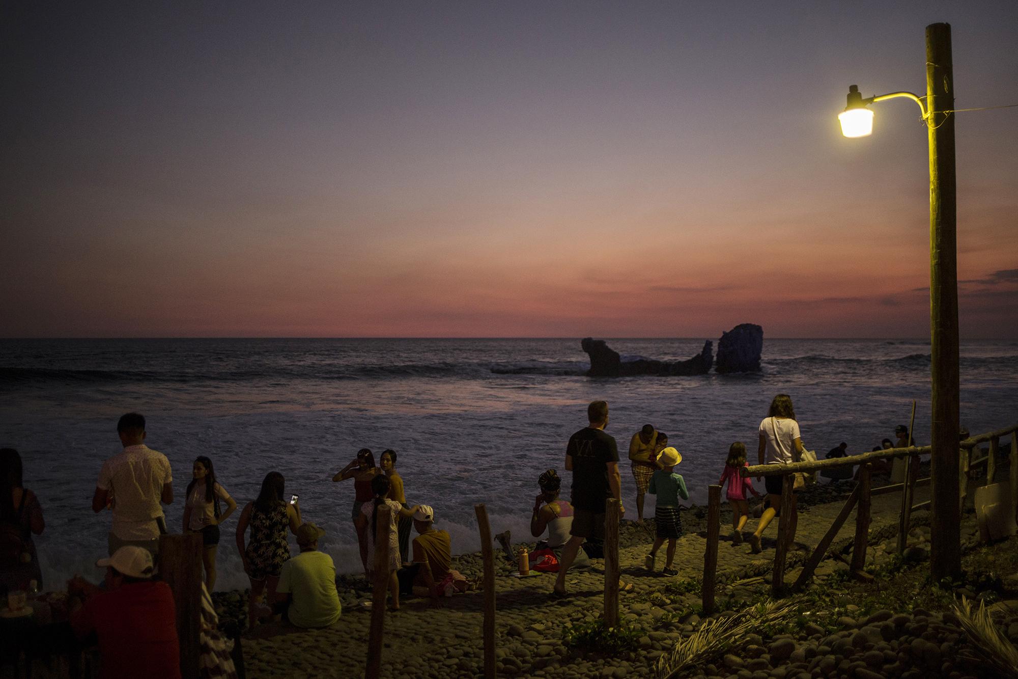 Un vendedor de minutas había vendido solo tres dólares durante el domingo frente al mar. Al final de la tarde, le fue mucho mejor y obtuvo 10 dólares más gracias a que la gente se acumuló en la playa El Tunco para ver el atardecer en un país en estado de excepción.