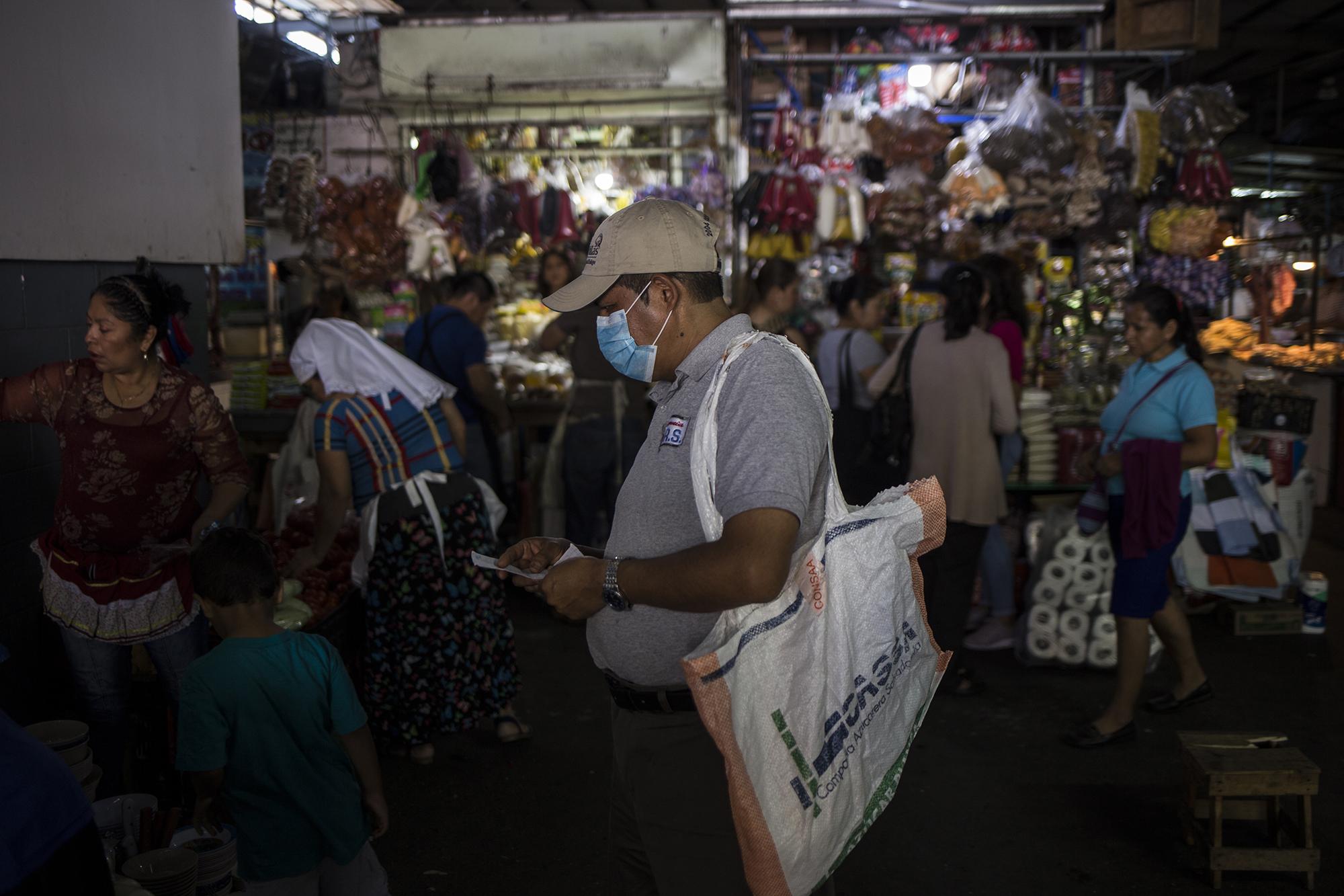 Pese a el anuncio de la Policía Nacional Civil, de controlar el flujo de personas en los mercados municipales, en Santa Tecla, comerciantes y consumidores abarrotan su mercado como en día normal. En la imagen, un hombre realizaba sus compras en medio de la multitud que caminaba en los pasillos de ese centro de comercio, el lunes 16 de mar5zo. Foto de El Faro: Víctor Peña.