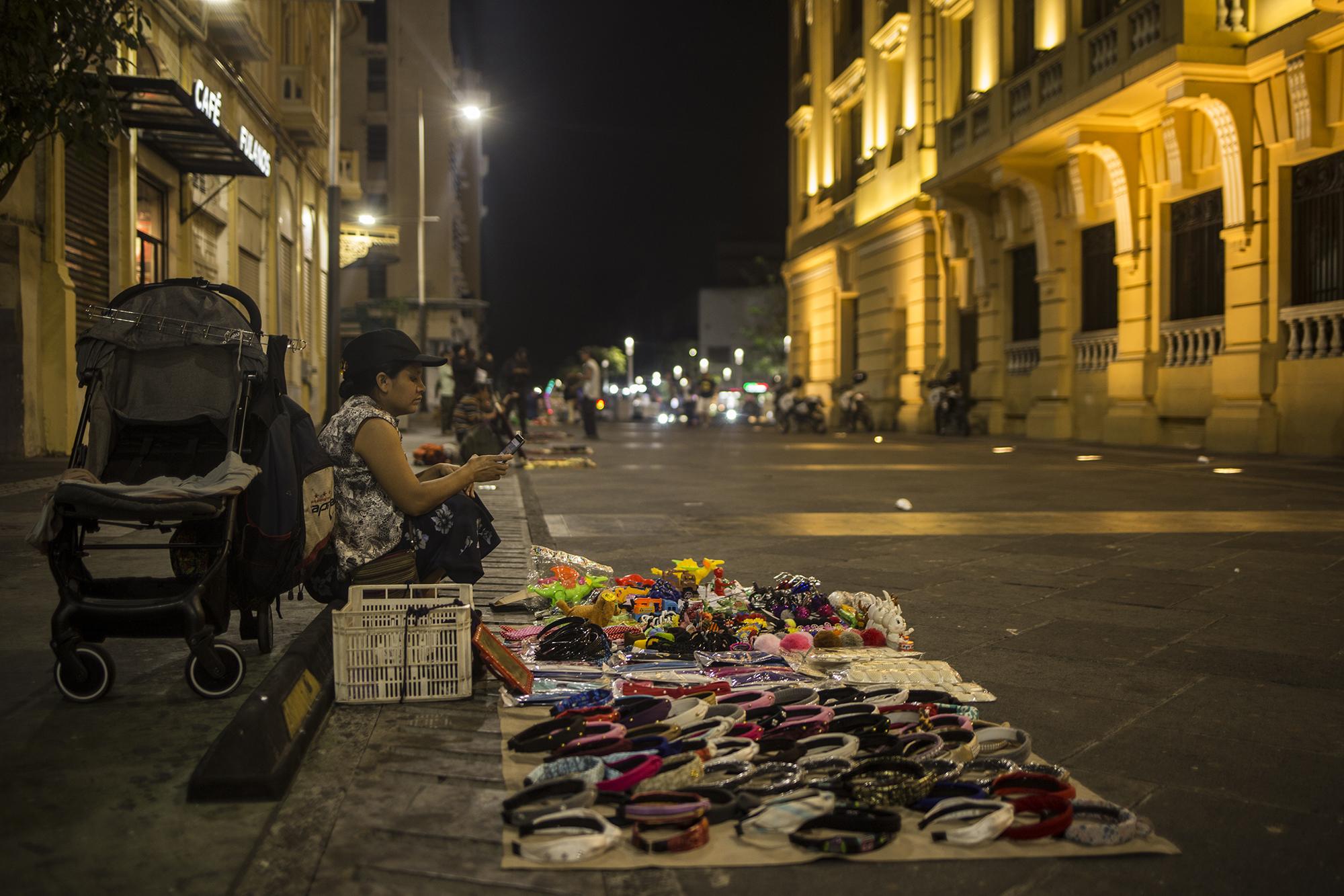 Roxana Fernández, de 32 años, viaja a diario desde el municipio de Soyapango hasta el Centro Histórico de San Salvador para comercializar accesorios para el cabello. Para Roxana es complicado dejar de vender sus productos. Con la emergencia por COVI-19 sus ventas han bajado en los últimos días. La necesidad de Roxana es tan grande, pero advierte que tomará riesgos para vender y lograr conseguir algo para comer. Foto de El Faro: Víctor Peña. 