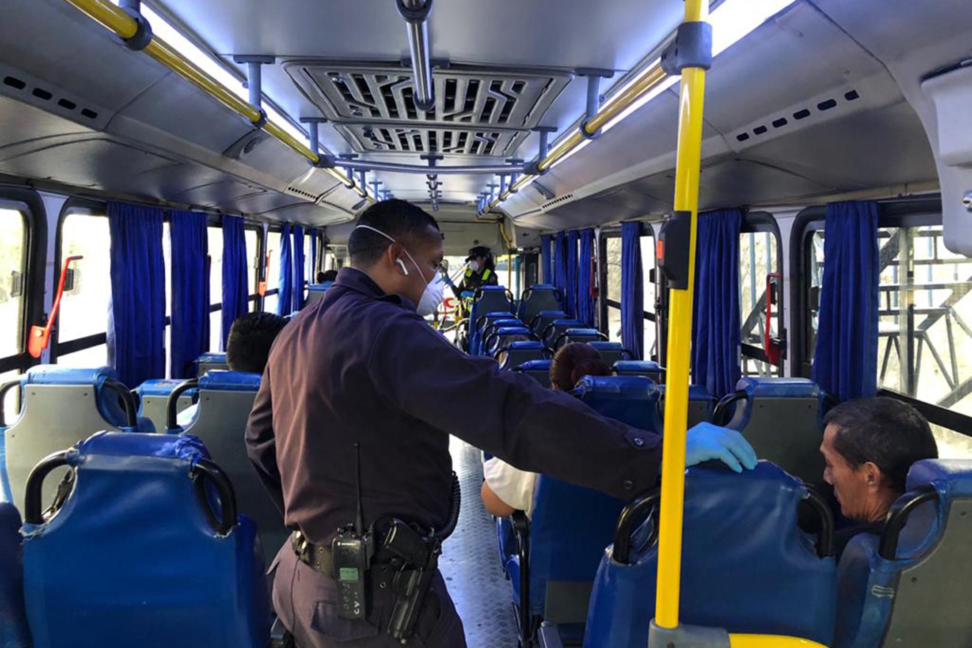 En un retén colocado en la Avenida Juan Pablo II, la Policía revisa que los autobuses cumplan con las reglas sanitarias y que los pasajeros tengan una buena excusa para circular durante la cuarentena. Foto de El Faro: Carlos Martínez.   
