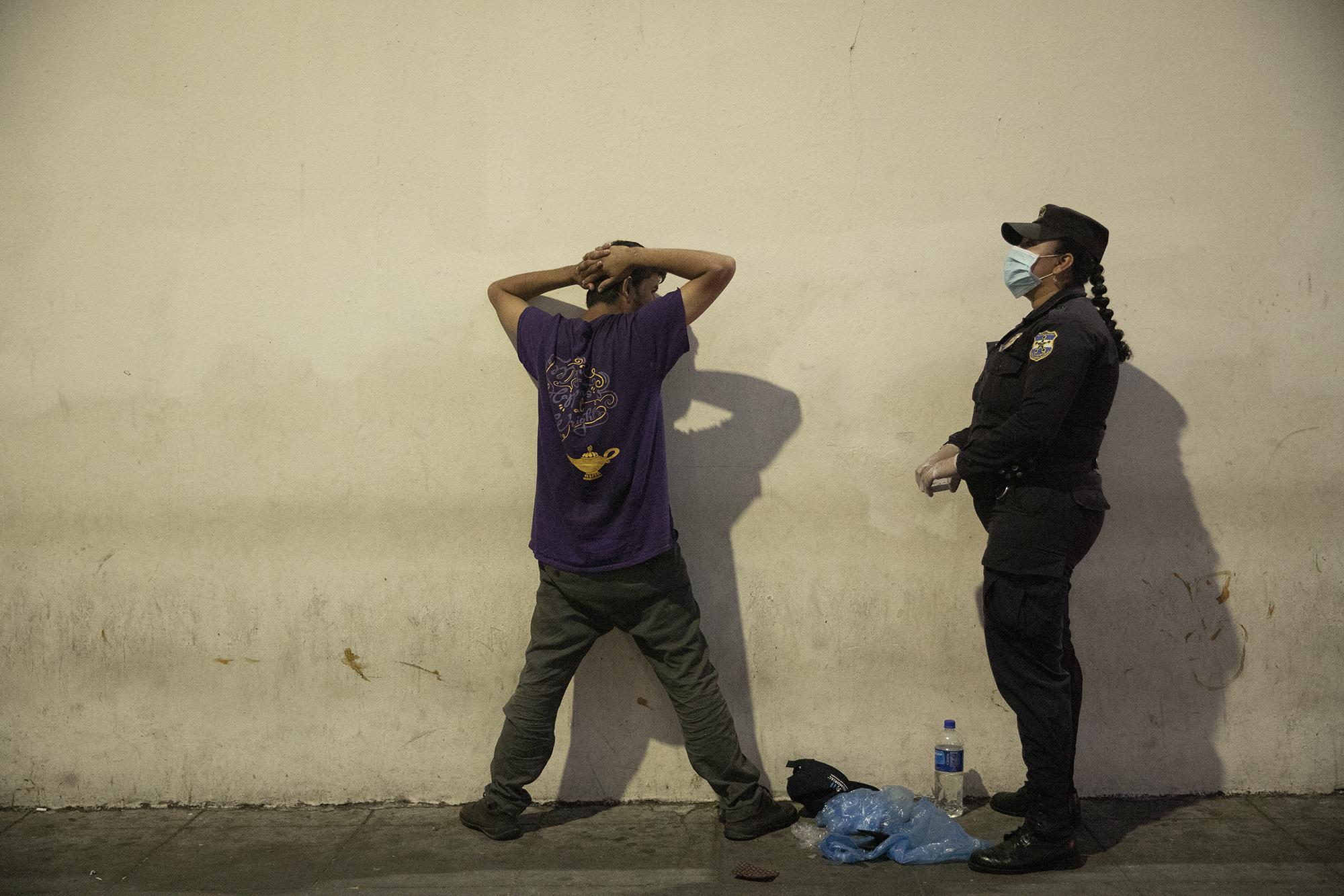 Una agente de la Policía detiene a un hombre que circulaba en los alrededores de la plaza Gerardo Barrios, en el centro de la capital. El hombre no pudo justificar la razón por la cual andaba en las calles en la noche del 22 de marzo. Los agentes lo remitieron a la delegación Centro, para luego ser trasladado a uno de los centros de contención de la capital. Foto de El Faro: Carlos Barrera