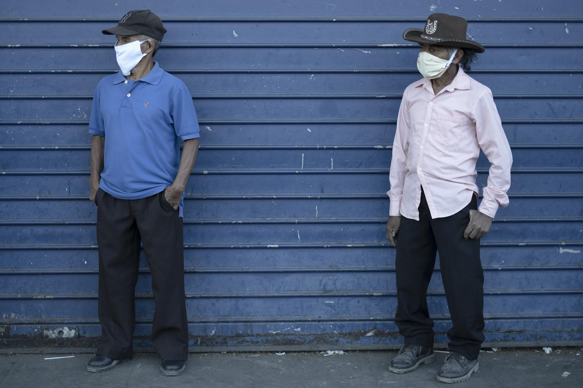 José Hernández, de 68 años, y Efraín Ramirez, de 70, viajaron desde Cojutepeque hasta el Banco Hipotecario ubicado en el Centro Histórico. Los dos usaban mascarillas de tela que les hicieron sus esposas. Según dijeron, las farmacias a las que fueron a comprar no tenían. Foto de El Faro: Carlos Barrera