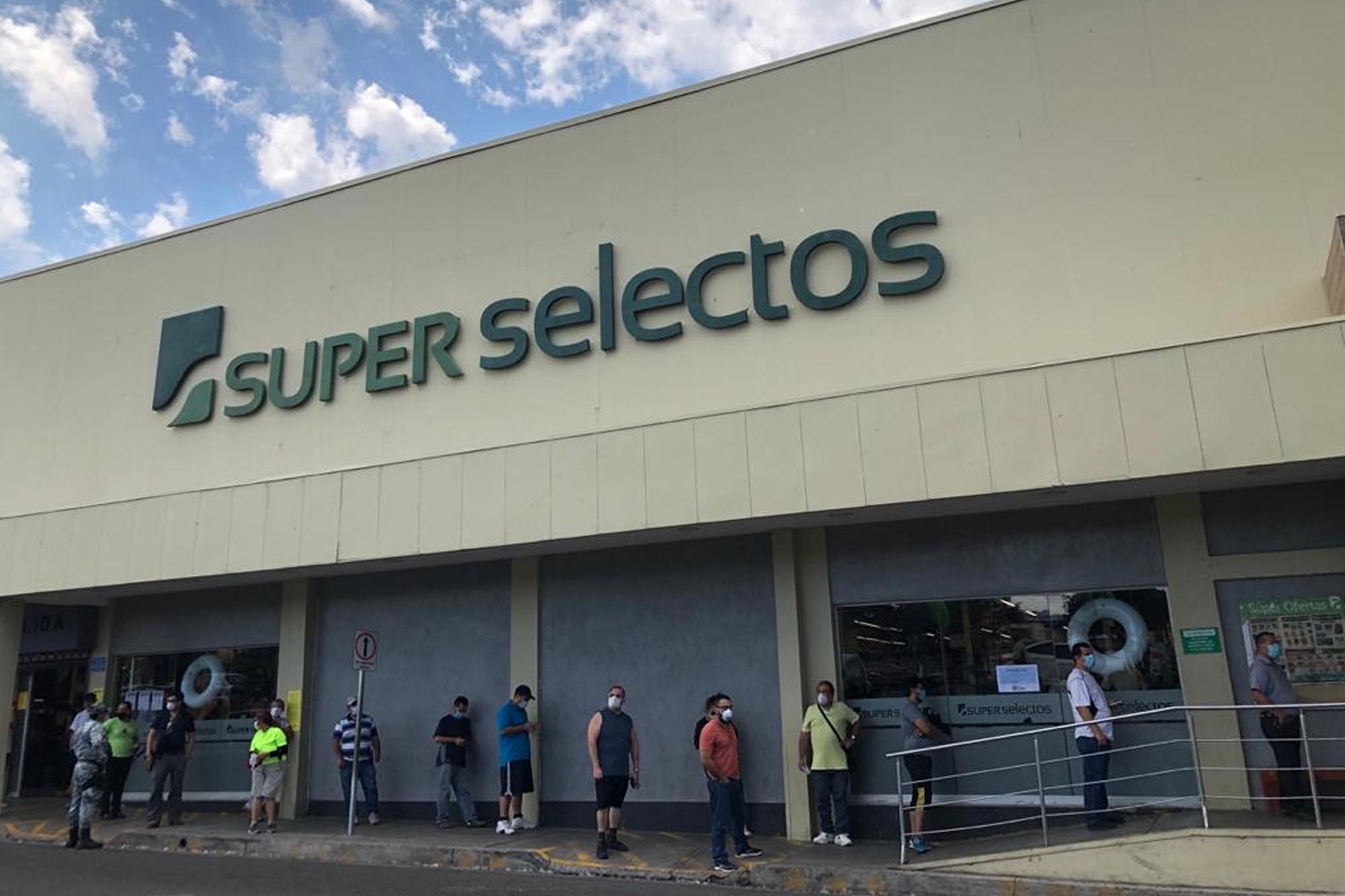 En el Súper Selectos de la colonia San Luis, las personas hacen fila para entrar. Afuera del centro comercial han sido desalojados todos los pequeños vendedores que solían ocupar la acera para sus ventas de subsistencia. Foto de El Faro: Carlos Martínez