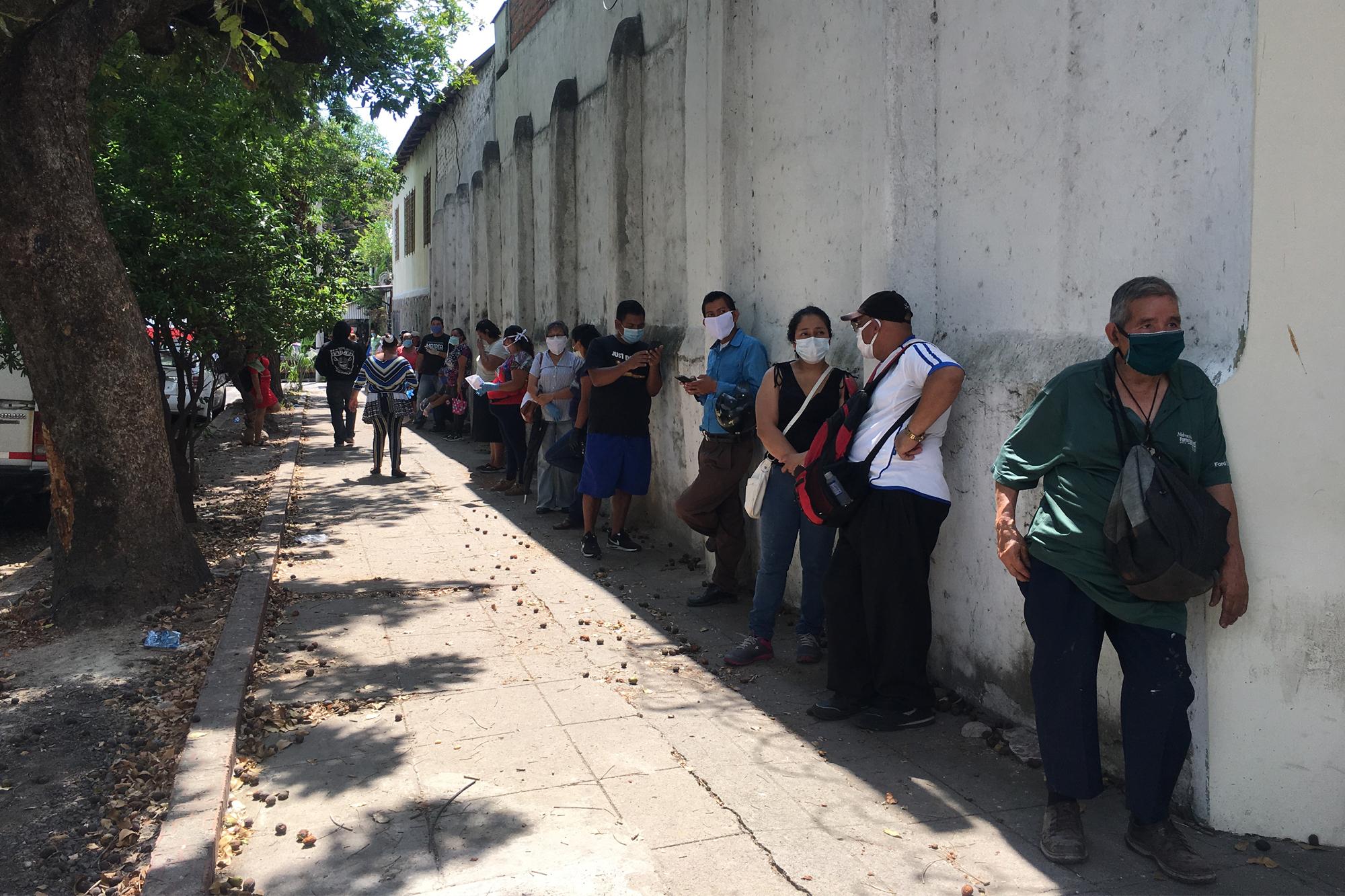 Cerca de un centenar de personas, que en algunos casos viajaron horas para llegar a la capital, hicieron fila el sábado por la mañana ante las oficinas del CENADE en San Salvador. Foto de El Faro/Valeria Guzmán