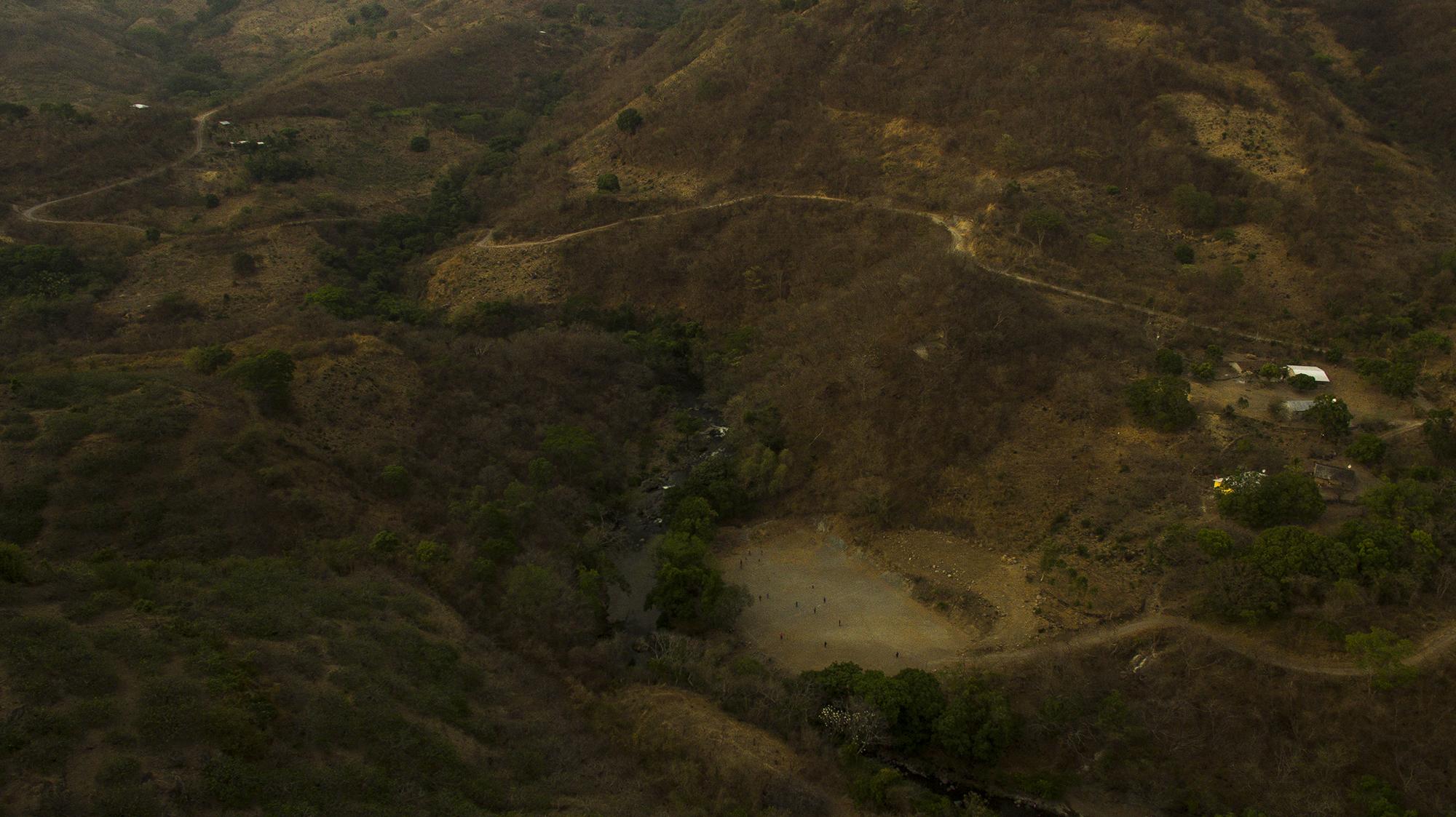 Justo en esta zona de San Lorenzo se unen El Salvador y Guatemala. Hay un sinfín de puntos ciegos entre ambos países. A la derecha, en la imagen, es Guatemala. Tanto El Salvador como Guatemala viven situaciones excepcionales, que restringen la circulación de sus habitantes y cierran fronteras. Los productores de jocotes han dejado en el abandono hasta 80 manzanas de cosecha, debido a la falta de posibilidades de movilidad. Una buena parte de los pobladores de las aldeas guatemaltecas trabajan del lado salvadoreño durante la recolección. En esta cosecha ha sido imposible. La Fuerza Armada ha montado bases para evitar el paso libre a lo largo del río San Lorenzo, que divide a ambos países.