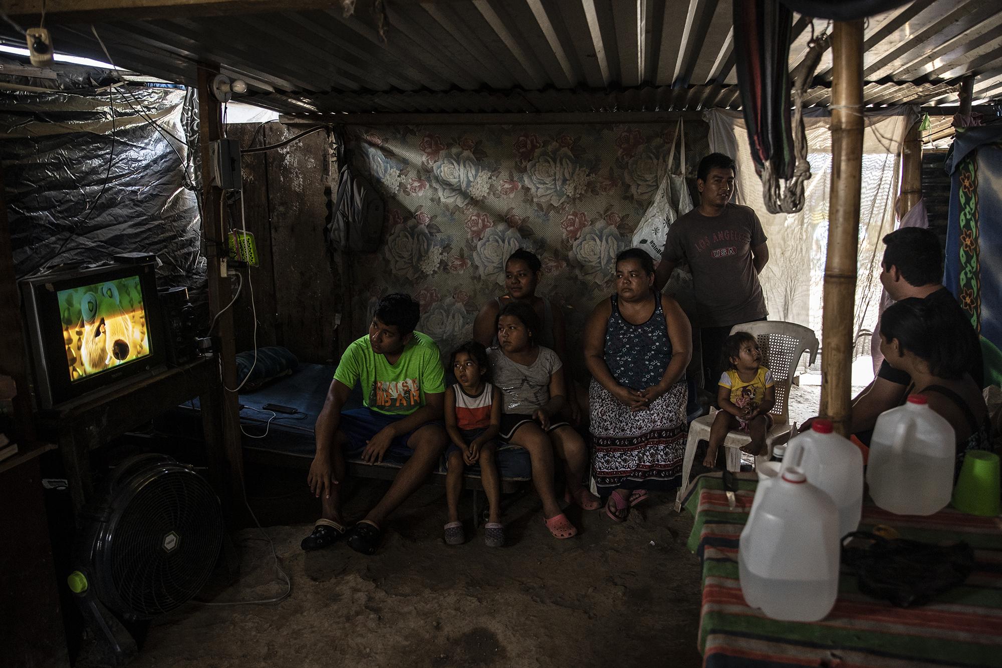 Norma Vásquez tiene 53 años, es madre, abuela y cabeza de hogar en una casa donde viven diez personas. La casa de la familia Vásquez es una pequeña caja formada por láminas y bambú. La sala también funciona como dormitorio y comedor. Debido a que los miembros en edad de trabajar pertenecen al sector informal, todos se han quedado sin ingresos por no poder salir de casa. De la familia Vásquez nadie fue favorecida con los $300 que el gobierno brindará a las familias para apalear la crisis económica causada por la pandemia del coronavirus, 