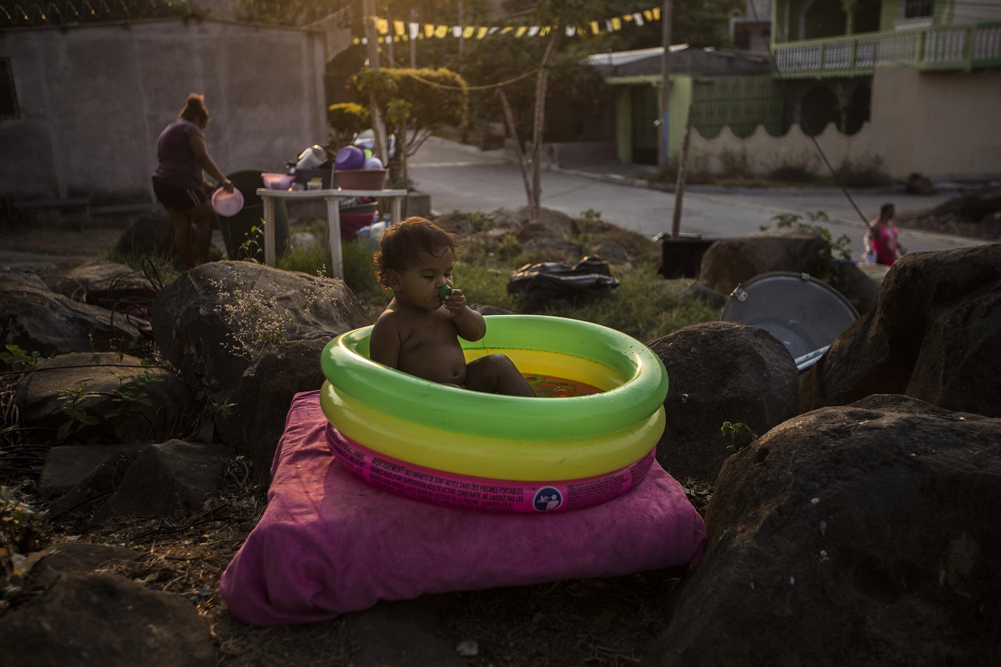 Calec Osorto, de un año y medio, es hijo y nieto de payasos del circo Wonder Boys. Es también parte del show: aparece como el payaso Semillita. En la imagen, Calec toma un baño en su pequeña piscina inflable, la tarde del martes 21 de abril, a unos diez metros de la carpa del circo donde sobreviven a la cuarentena.